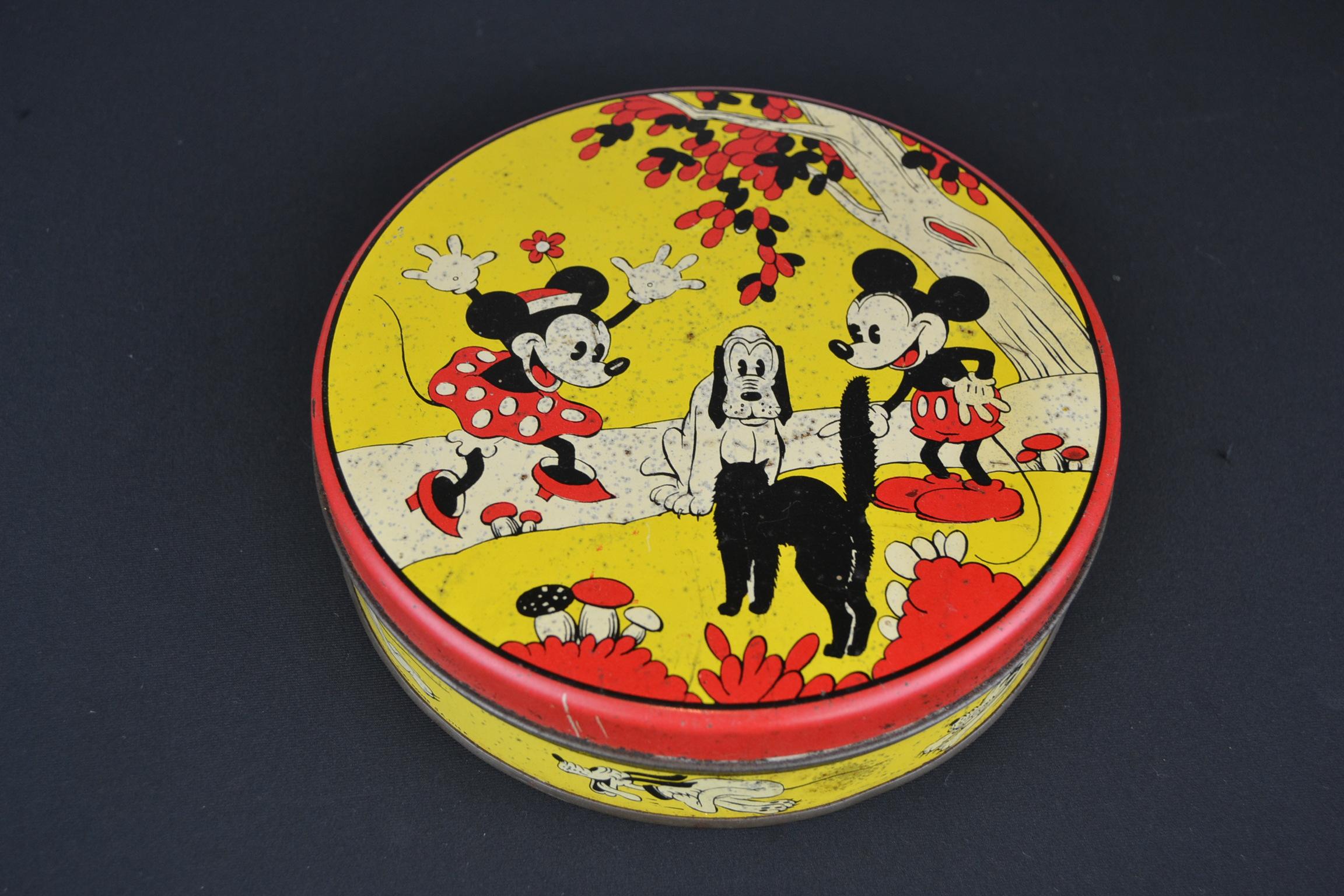 boîte de conserve Walt Disney des années 1930 avec Mickey Mouse, Minnie Mouse, Pluto et le chat.
Cette boîte ronde jaune lithographique présente de belles images des célèbres personnages de Walt Disney Animation. 
Combinaison de couleurs rouge,