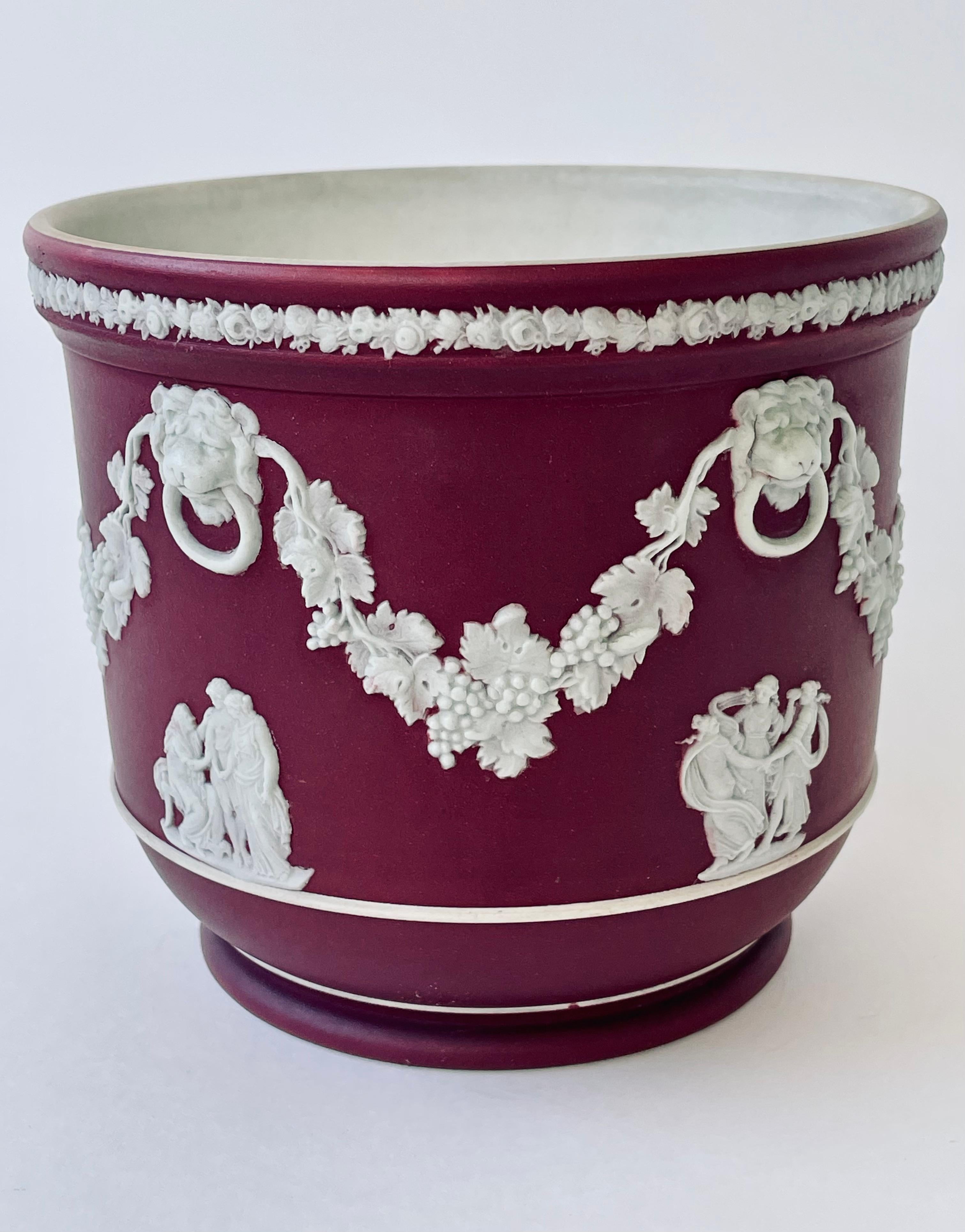 Etruria, Staffordshire, 1929-1938 , turned Wedgwood shape no. 317, stoneware with crimson Jasper dip ground, decorated with sprigged white Jasper bas-relief classical cameos, ringed lion's masks with grapevine festoons, the rim wreathed in flowers,