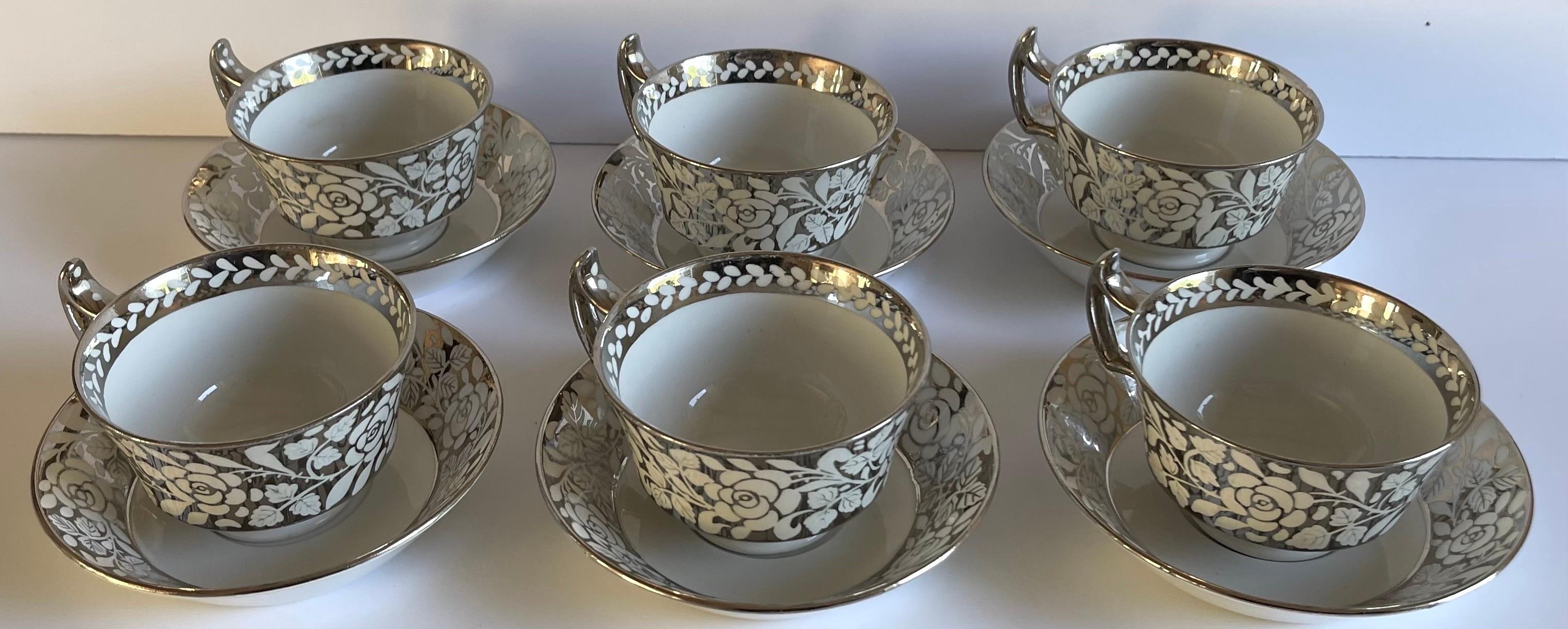 Set of six 1930s Wedgwood lusterware tea cups and saucers. Overall silver floral motif on bone China background. Set includes 6 tea cups and 6 saucers, 12 pieces total. 
Each piece is stamped Wedgwood on the underside. 
Each teacup measures: 4” wide