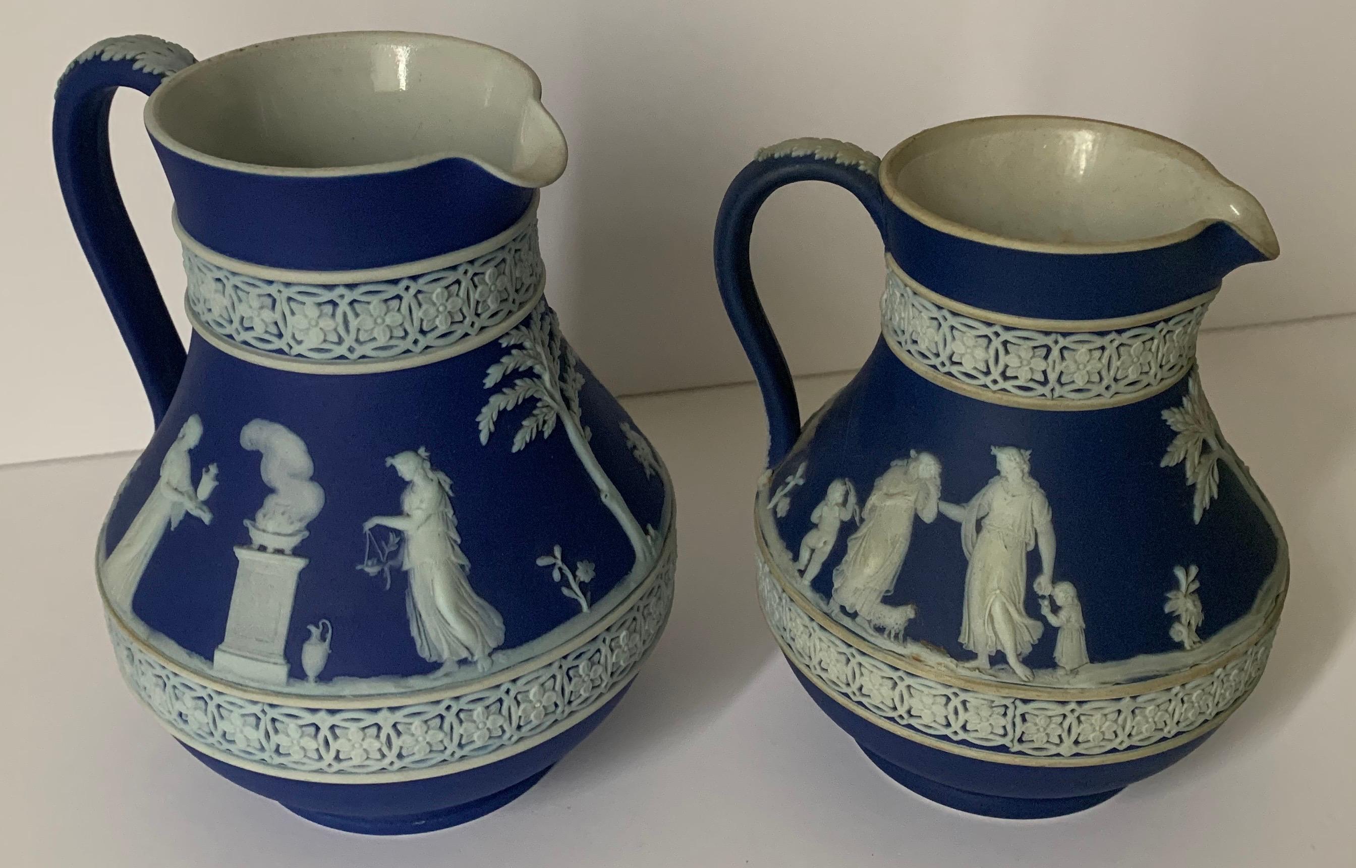 Set of 2 1930s Wedgwood jasperware pitchers. Each pitcher features a neoclassical motif. Each pitcher stamped Wedgwood on the underside and stamped 30/ 36 (as shown) indicating they were made in the 1930s. Set included 2 dark blue jaspwerware