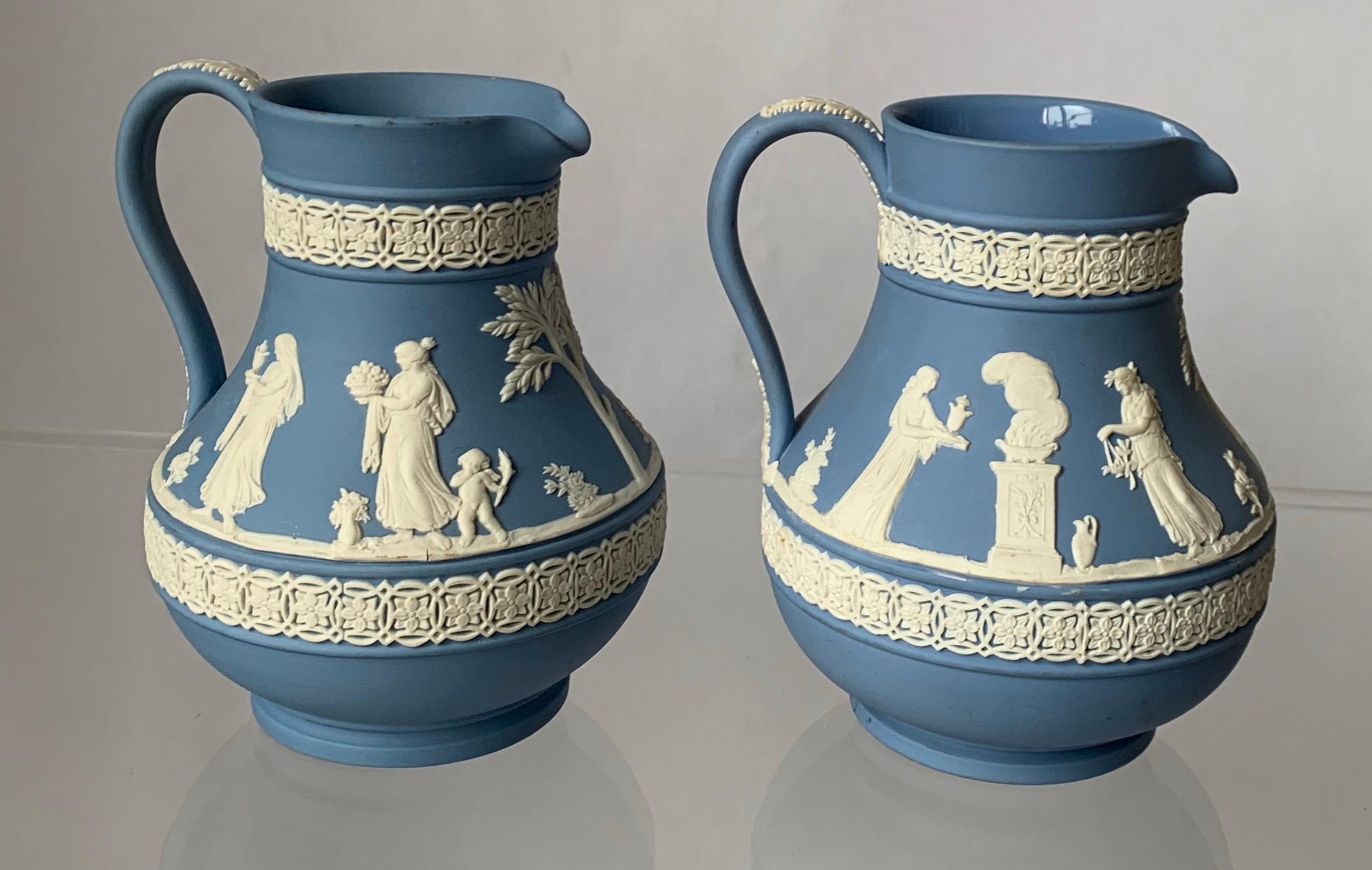 Set of 2 1930s Wedgwood jasperware pitchers. Each pitcher features a neoclassical motif. The pitcher on the right has a glazed interior. Each pitcher stamped Wedgwood on the underside and stamped 35/ 36 (as shown) indicating they were made in the