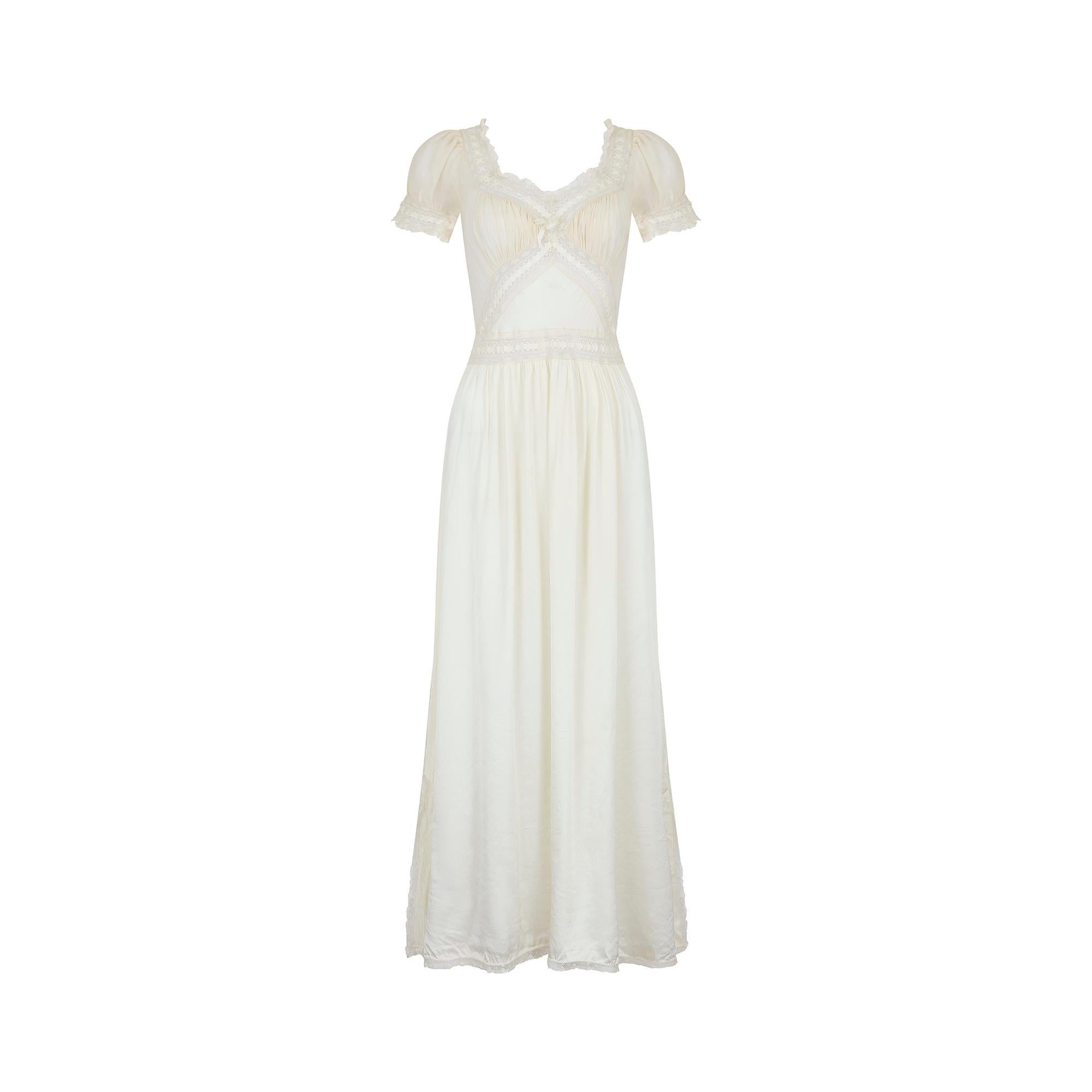An incredible example of trousseau lingerie from the late 1930s or early 1940s.  This charmeuse rayon dress in a delicate shade of pale cream with white ribbon detail; it is ever so slightly sheer. It features a gathered bust section, sewn in an