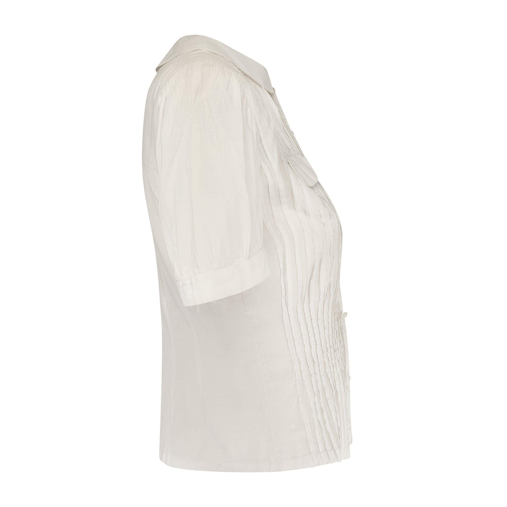 Una delle migliori camicette in cotone anni '30 che abbiamo mai avuto da CIRCA. Realizzato con una leggera mousseline di cotone bianco che è stata plissettata e rimboccata di rosa sul pannello frontale. Superbamente aderente, ha le maniche a sbuffo,