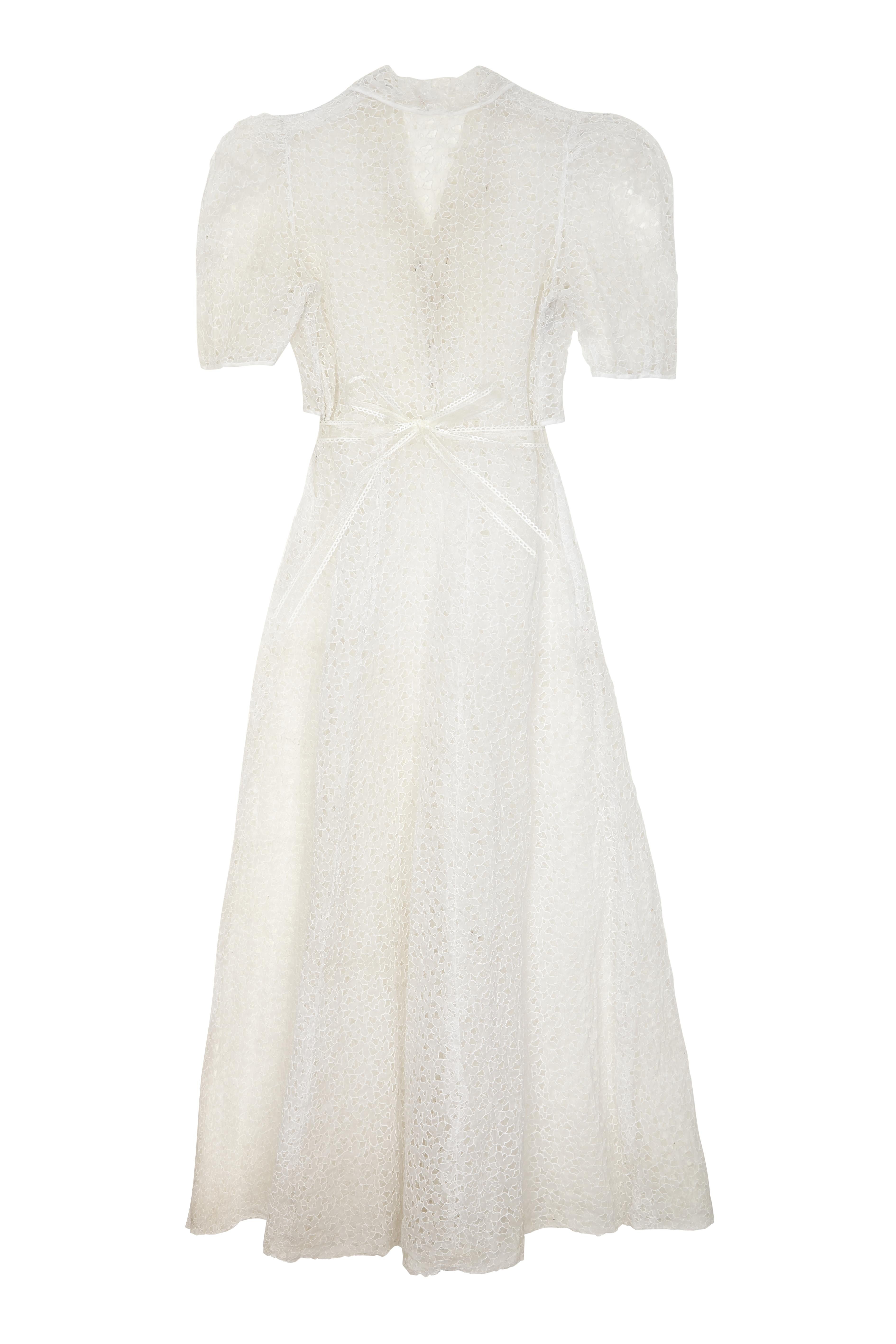 This is a magnificent example of a 1930s cut-out work, organza dress in really pristine vintage condition. It is an archetypal 1930s shirt-waister design that reaches ankle length and has a full A-line skirt. The entire design is a repeat cut out
