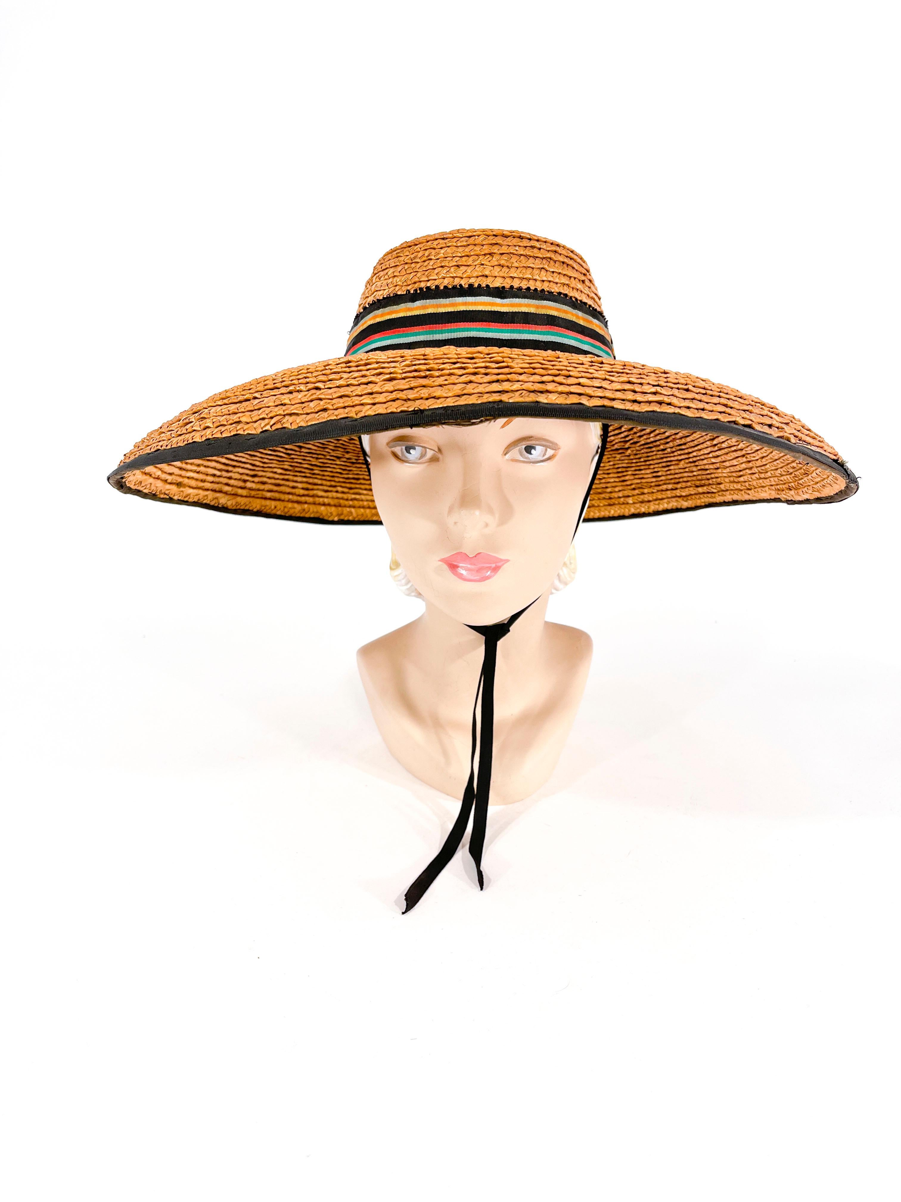 1930er Jahre Geflochtener, breitkrempiger Sonnen-/Bilderhut aus Stroh, verziert mit einem marine- und regenbogenfarbenen, gestreiften Hutband mit Ziegelstein-Akzenten. Die Krempe ist vollständig mit Ripsband eingefasst, und das Innere der Krone ist