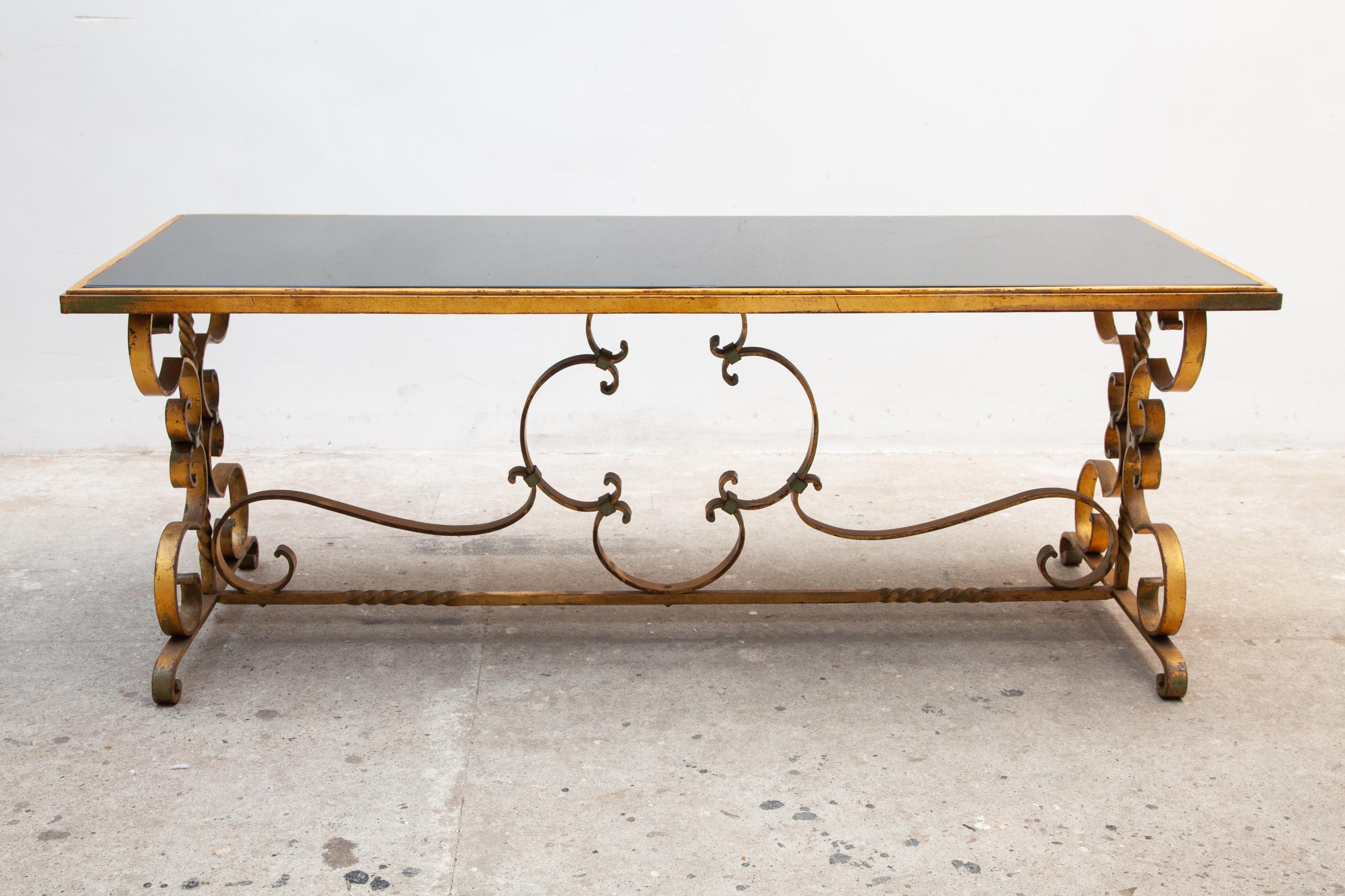 Magnifique table basse ou centrale Art Déco avec une base en fer forgé et les chaleureux détails d'origine dorés et fumés noirs du plateau en verre, design détaillé d'agréables courbes, très bel exemple d'Art Déco français des années 30

 