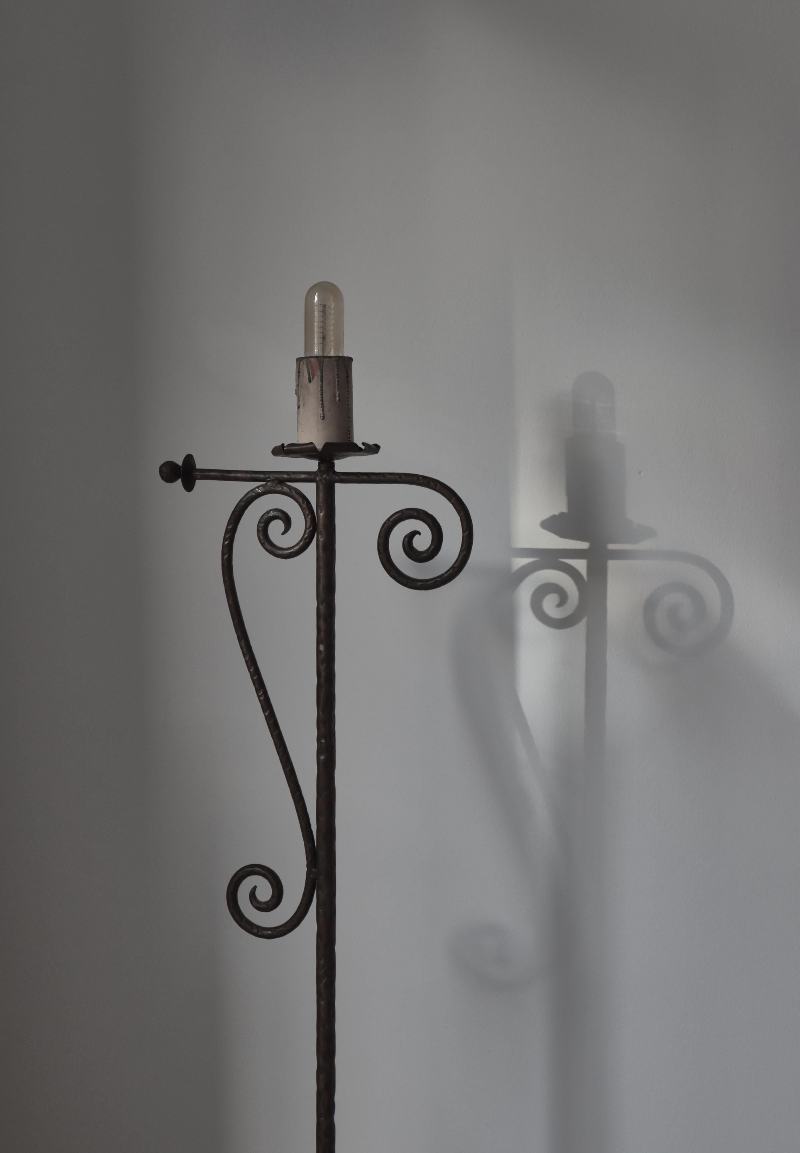 Wonderful 1930s floor lamp in the style of Taidetakomo Hakkarainen. Handmade in Denmark from wrought iron with wooden and painted faux candle at the top.
