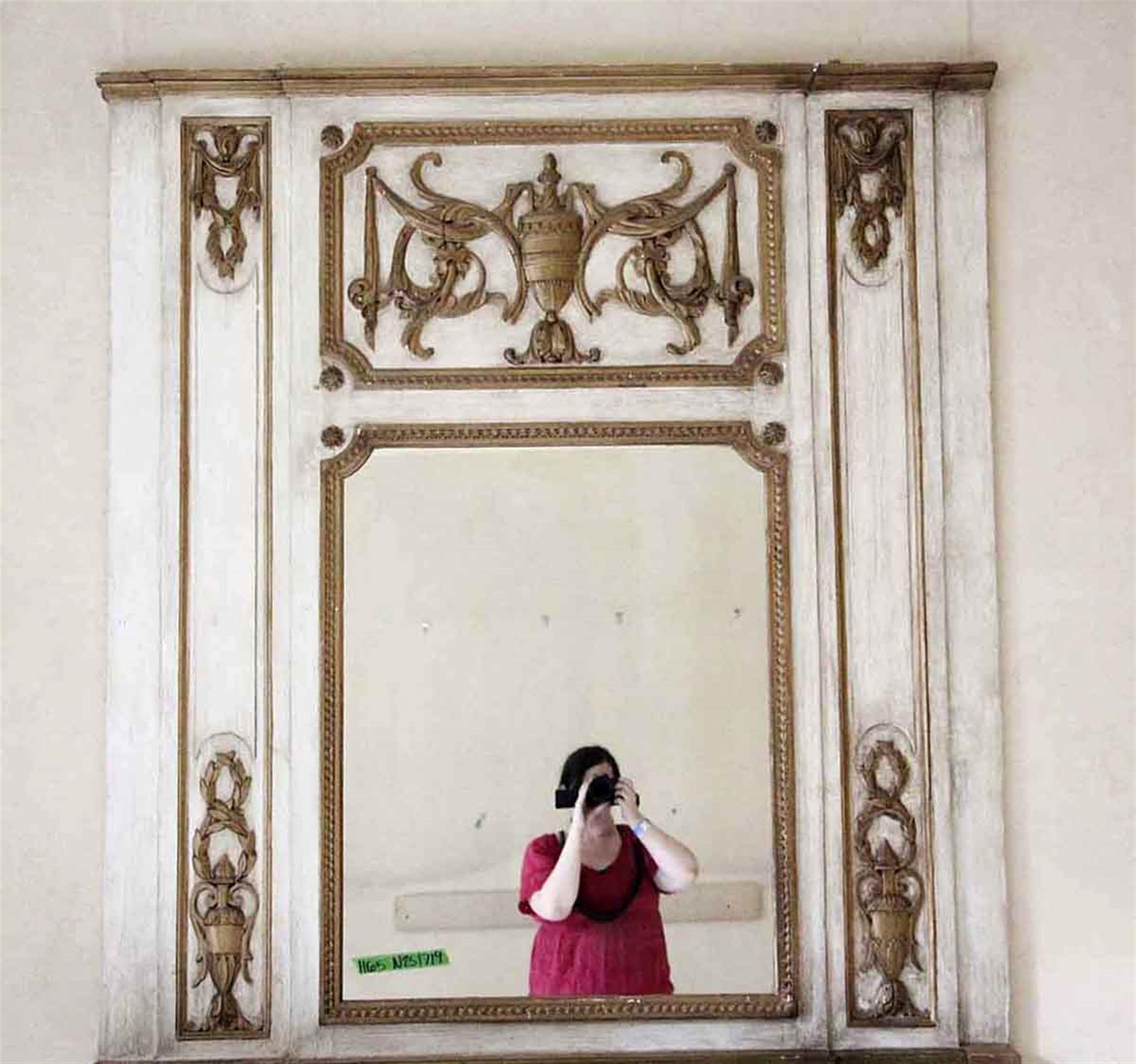 Decorative white wooden over mantel mirror with carved details and an urn in the top center from the 1931 NYC Waldorf Astoria Hotel. Originally from France and installed in room 1165. A Waldorf Astoria authenticity card included with your purchase.
