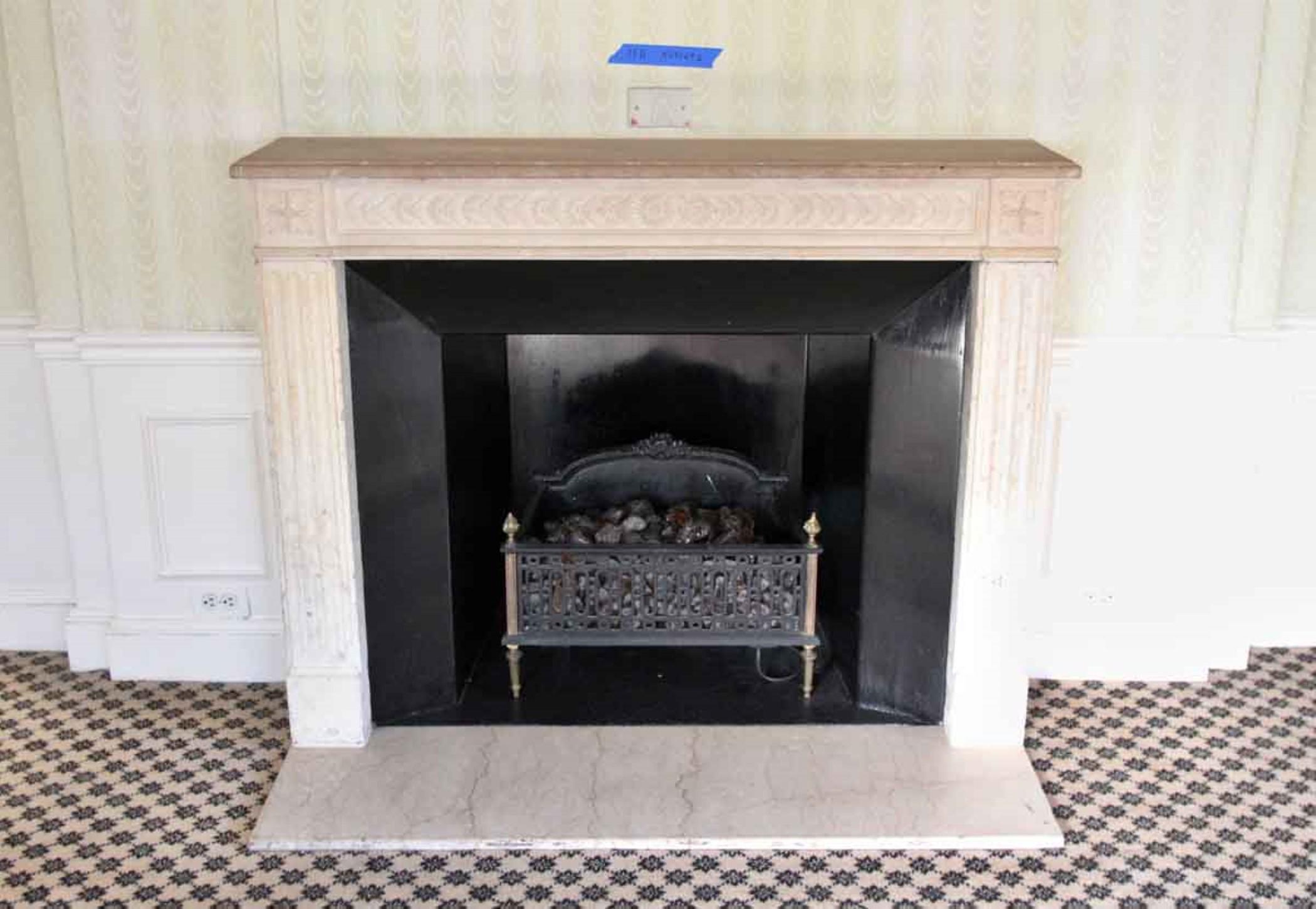 19th Century French made Louis XVI carved limestone mantel with a crema marfil marble hearth. This mantel was one of a group of antique mantels imported from Europe and installed in the Waldorf Astoria hotel in the 1930s when the hotel was first
