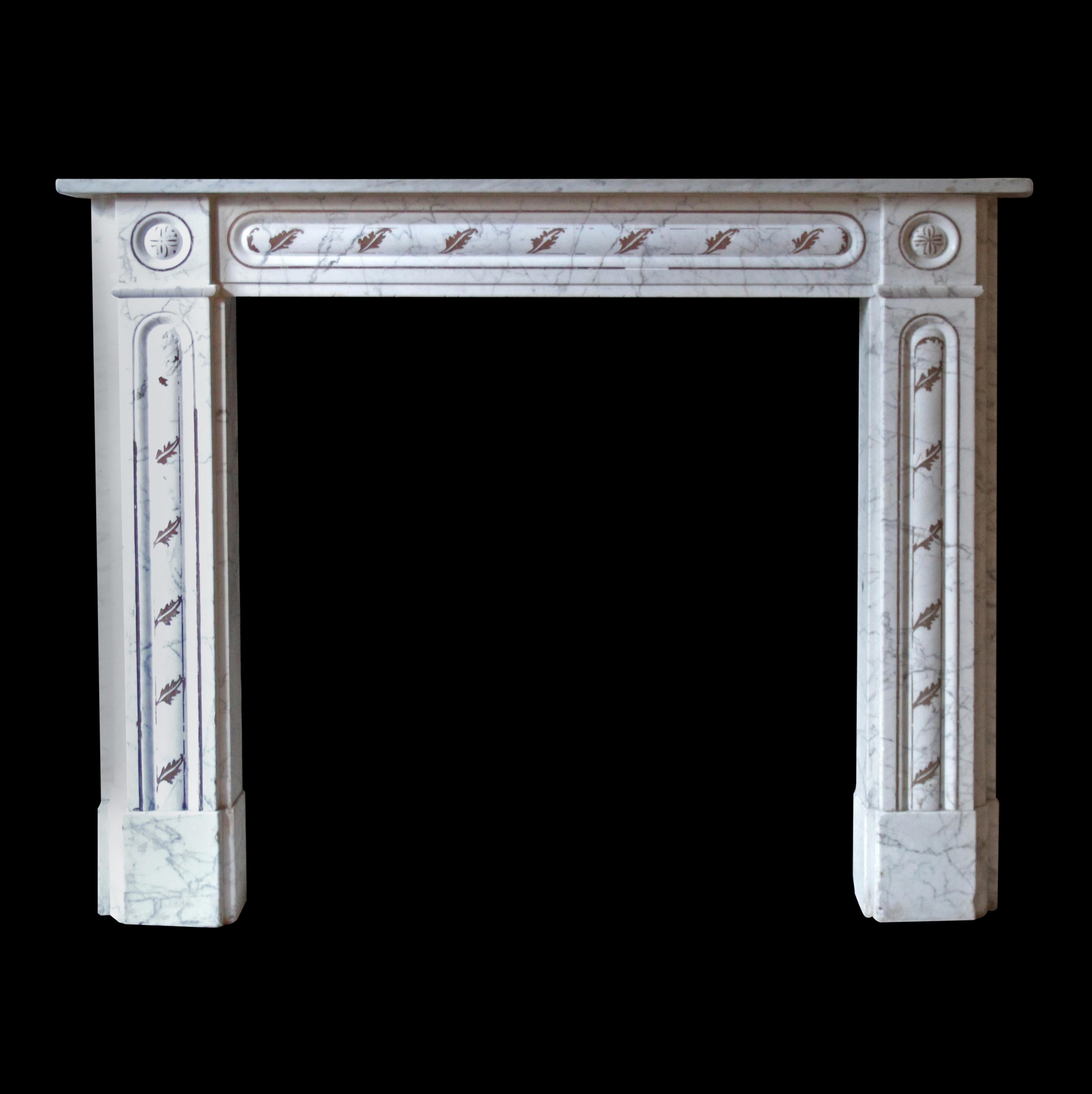 This English Regency style carrara white marble mantel is adorned with graceful gray veining that adds a touch of timeless elegance. An intricate decorative brown leaf detail graces the upper header and legs, enhancing its visual appeal. Among a