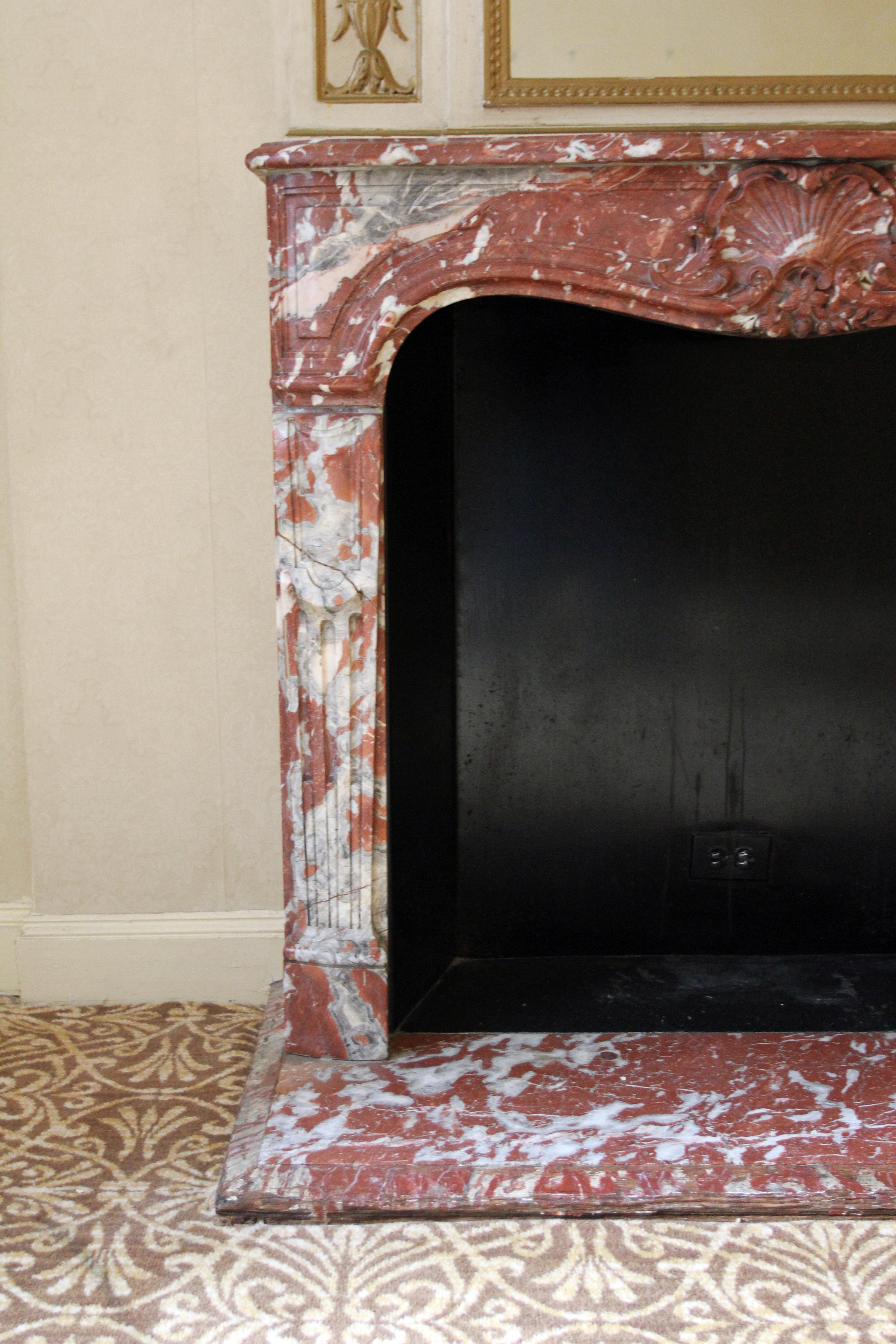 Hand carved French made 19th century Louis XV Rouge Royal Rococo marble mantel with original matching hearth. This mantel was one of a group of antique mantels imported from Europe and installed in the Waldorf Astoria hotel in 1931 when the hotel