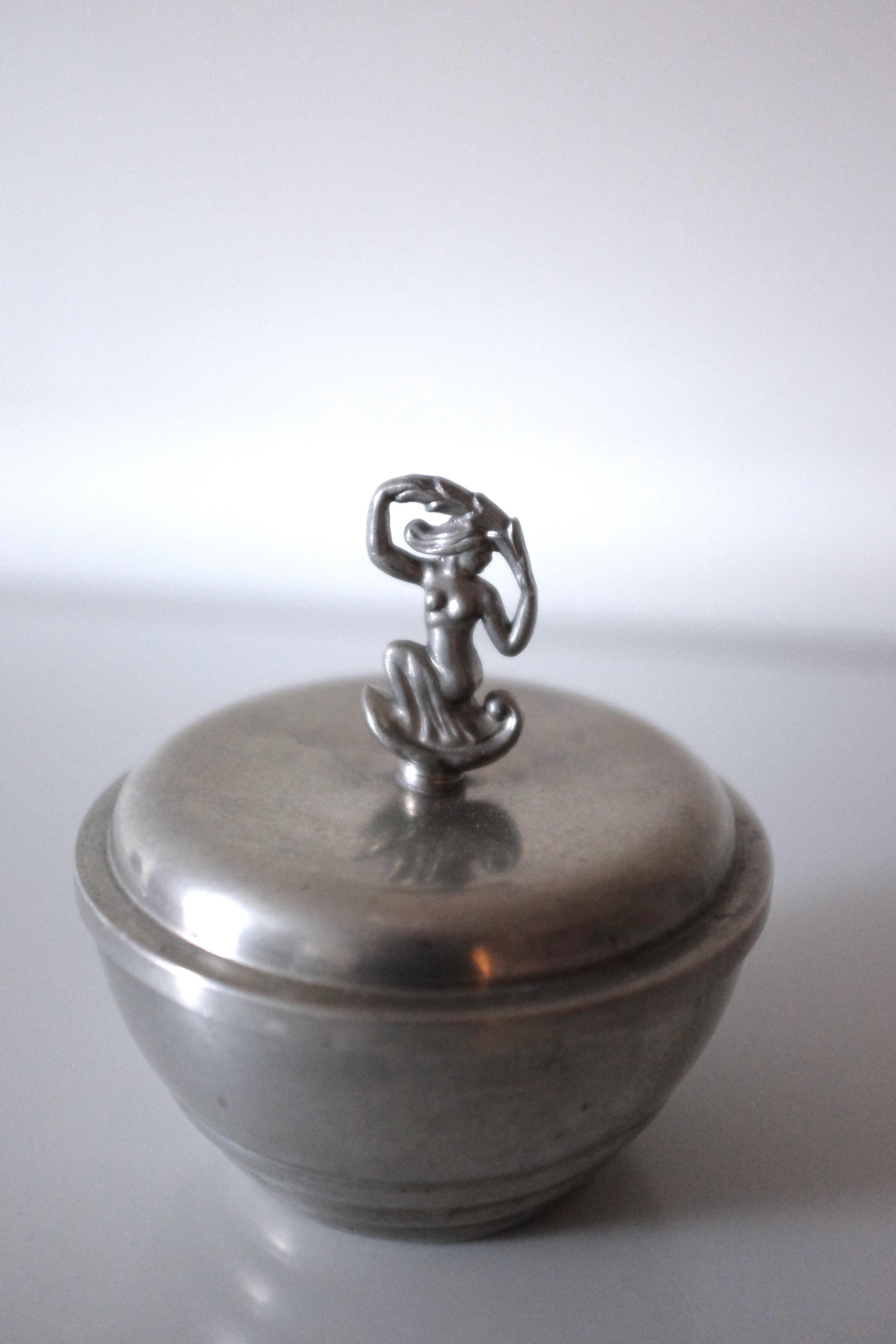 Gorgeous small vintage pewter jar from C.G Hallberg, Sweden, from 1932. Round shape with carved lines along the body and a decorative ornament on the top of the lid. The top lid has a small dent but not noticeable when closed. Manufacture marks at