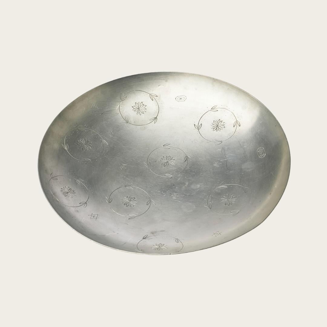 Il piatto con piede in peltro lucido, realizzato da Svenskt Tenn nel 1932, presenta un'elegante incisione di ghirlande e stelle. Contrassegnato dal produttore sul lato inferiore, reca un messaggio di regalo personalizzato datato 1933, che aggiunge