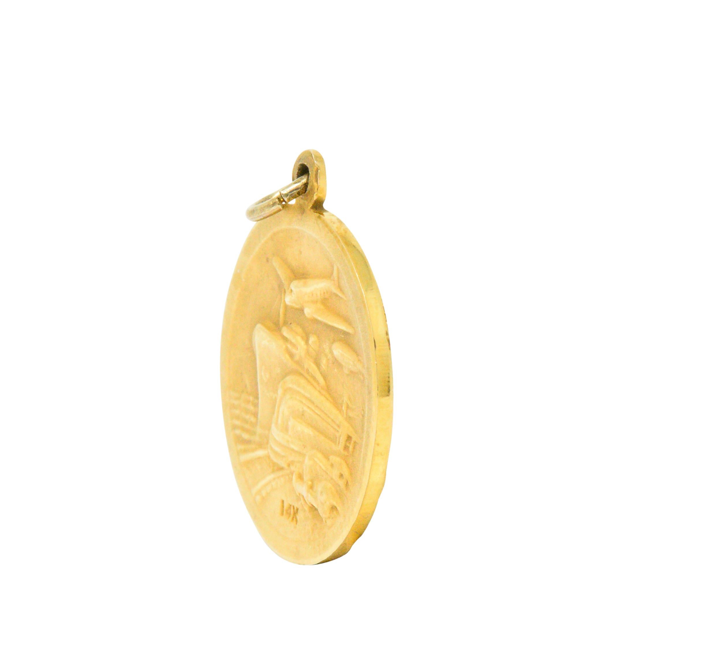 A gold pendant commemorating the 1933 Chicago World's Fair 

One side depicting the newest innovations of the time, new cars, trains, planes and ships

The other side depicts an old man on his knees with a staff and a baby with a globus cruciger