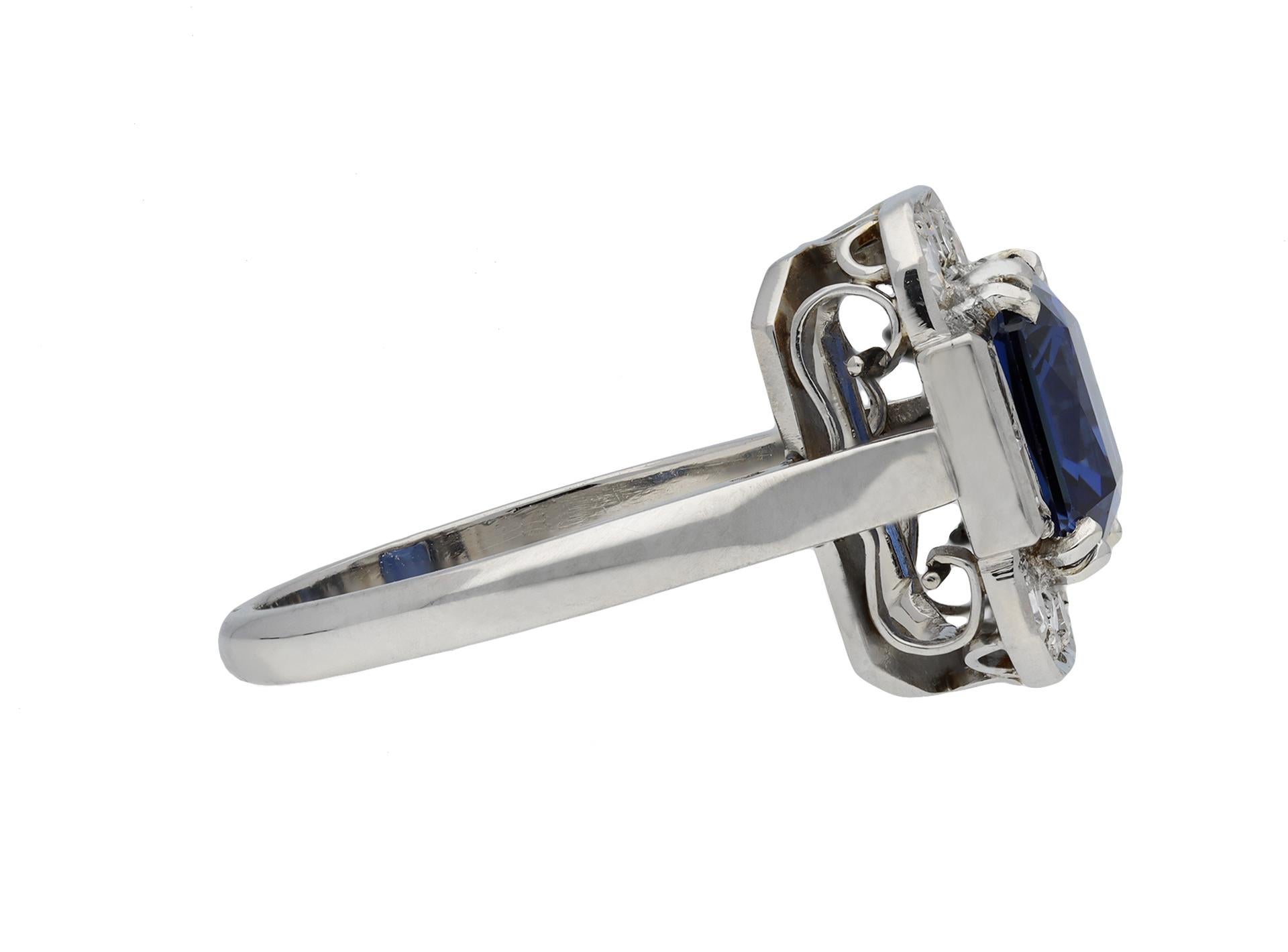 Art Deco sapphire and diamond ring. Set with an octagonal scissor cut natural unenhanced Ceylon sapphire in an open back double four claw setting with an approximate weight of 3.10 carats, flanked by four square step cut diamonds in open back