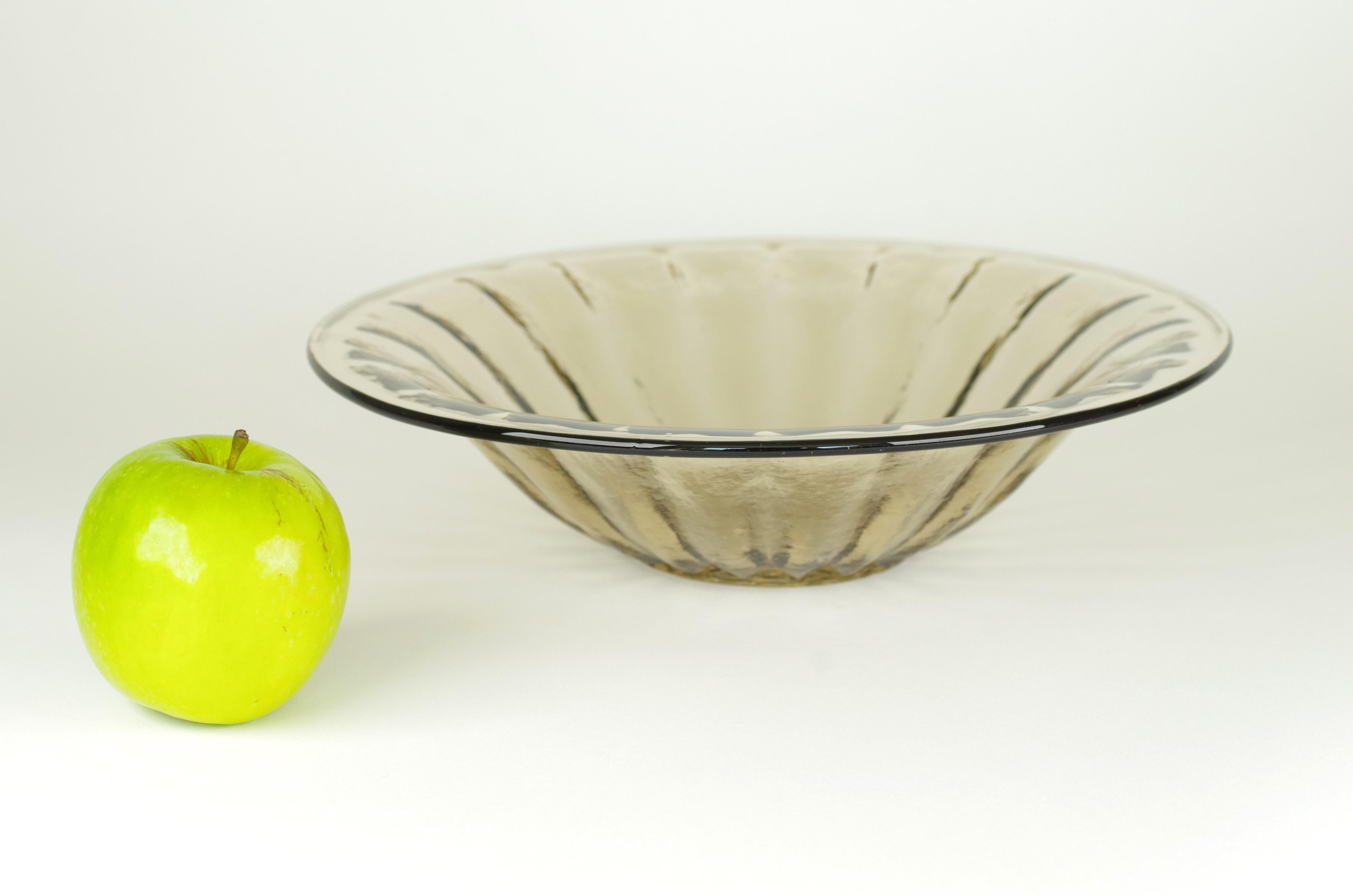 Product description:
This beautiful smoked glass fruit bowl from the Bambusa series of Kristalunie has been designed by Willem Jacob Rozendaal in 1935. The bowl has relief on the outside and is smooth on the inside. The Bambusa series consists of