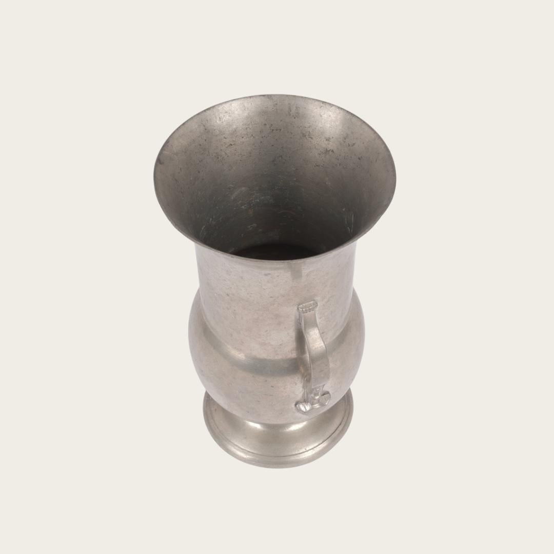This 1937 Pewter Vase by GAB Tenn features a Swedish Grace design with decorative handles. It is stamped GAB Tenn on the bottom and includes an engraved gift message dated 1938 on the vase.