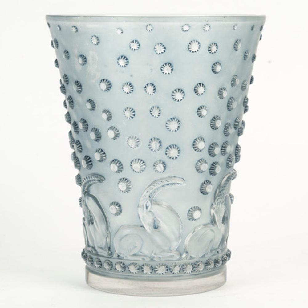 “Ajaccio” vase, model created in 1938 in pressed white glass with a blue patina, signed R. Lalique on the base.

Height: 20 cm 
(see cat. F. Marcilhac no. 10-914 p. 467).

Bibliography: Félix Marcilhac, R. LALIQUE, Catalogue raisonné de l'œuvre de