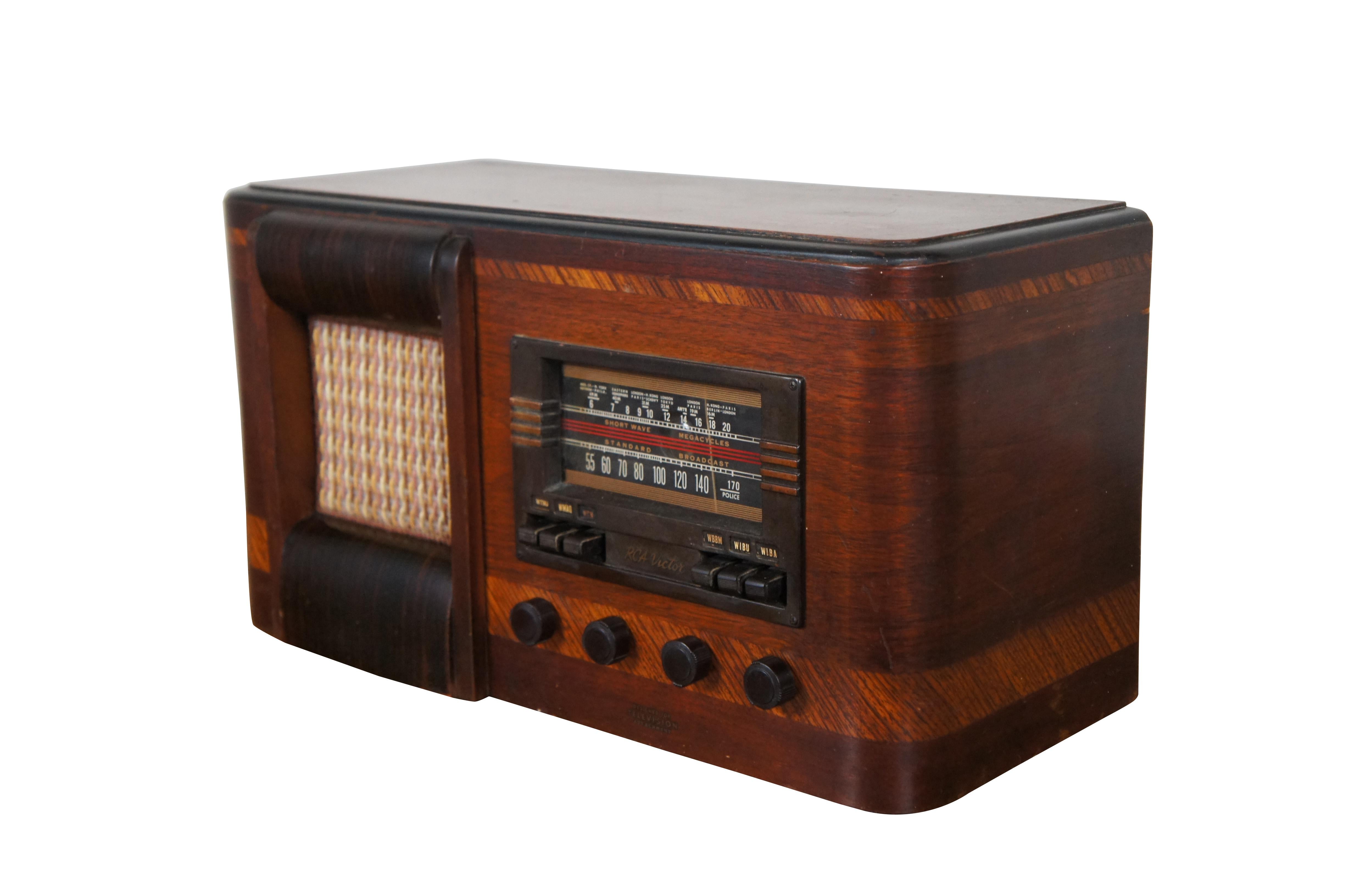 Antique 1939 RCA Victor Model T2 Superheterodyne tube radio, designed for use with records or television. Mahogany case features inlaid art deco styling with rounded corners and pink and yellow tweed speaker cover. 

Dimensions:
19
