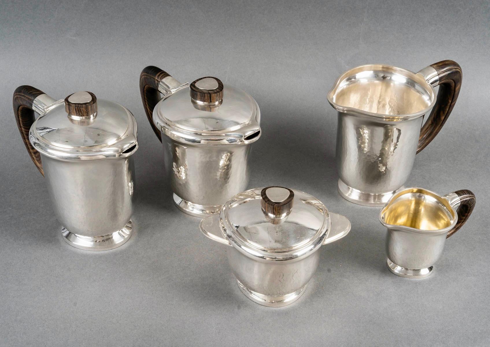 Art Deco tea and coffee set made in hammered sterling silver and rosewood by Georges Fouquet Lapar created in 1940s. 

Service including:
- a coffee pot 
- a tea pot
- a milkpot
- a sugar pot
- a jug

Minerve Solid Silver 950/1000 French mark -