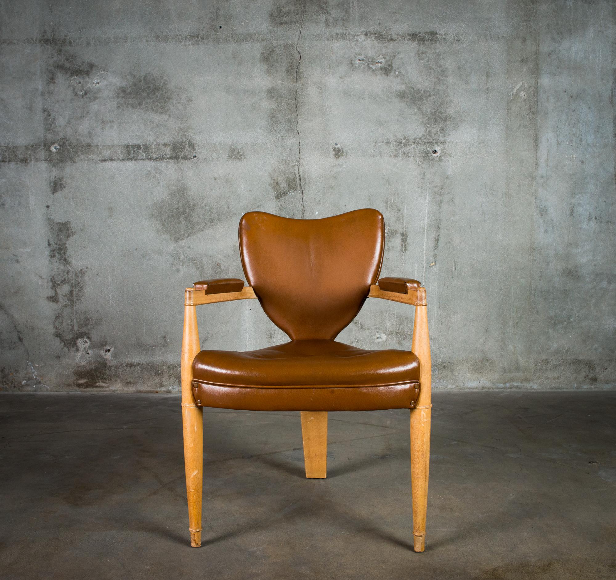 One French armchair with heart-shaped back, upholstered in leather, circa 1940.