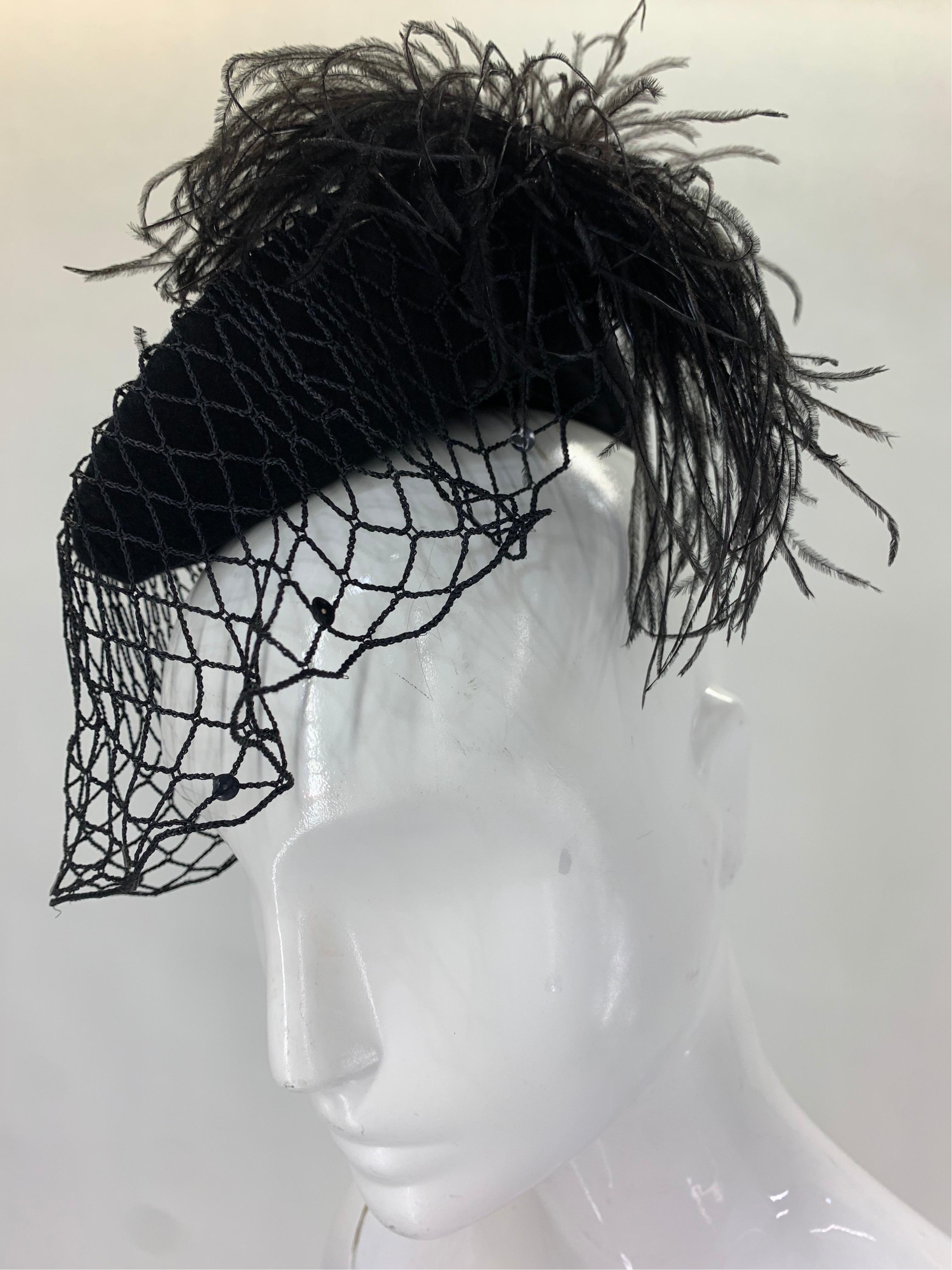 A fantastic 1940s riding-styled tilt hat in black with a charming ostrich feather that curls around the back to side of face. Thick crocheted veil edged in sequins.  One size fits all. 