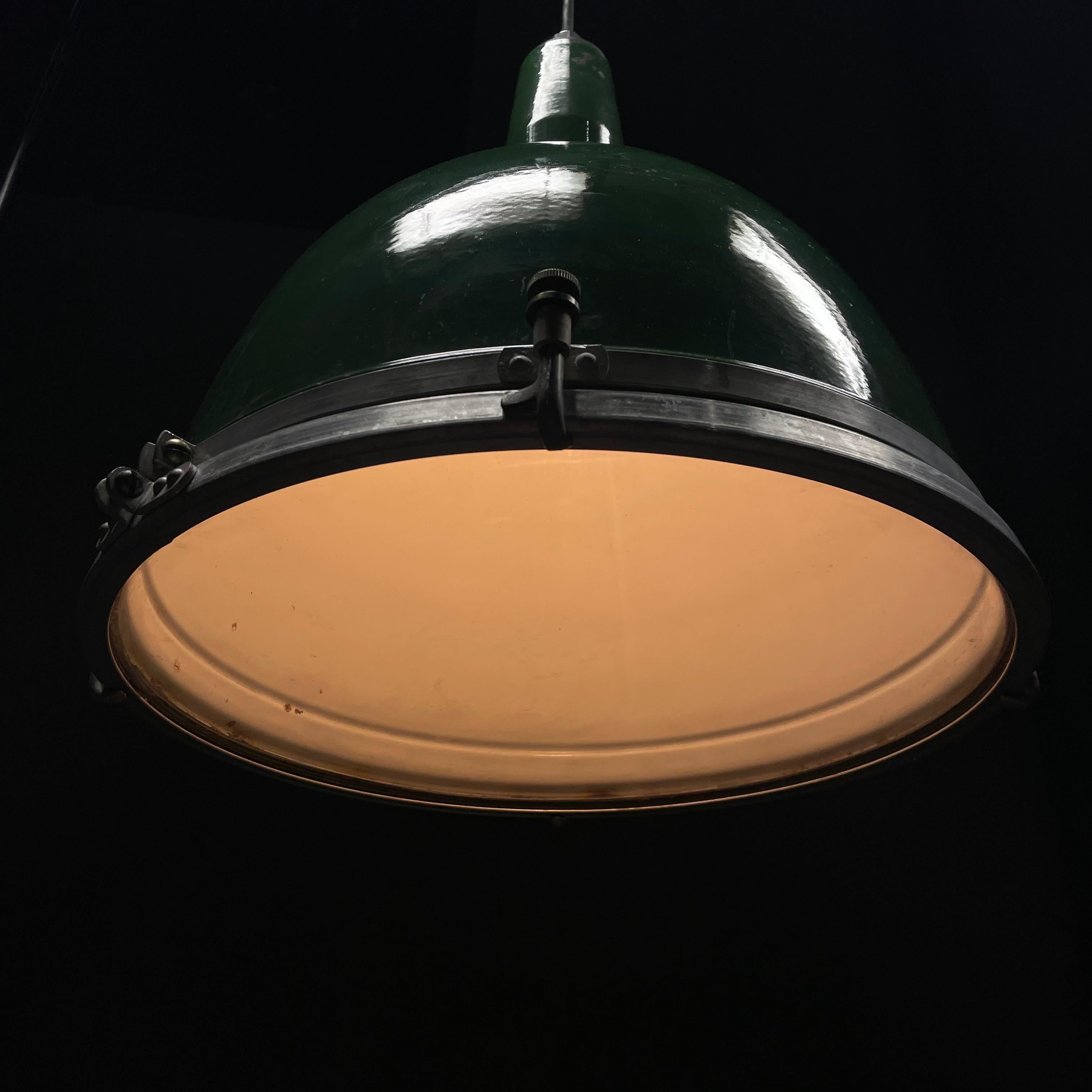 Un groupe de 20 lampes Goodrich fabriquées aux Etats-Unis.  Ces grandes lampes ont un système unique de lentilles en verre reliées à l'abat-jour en émail fixé avec des détails en laiton sur un anneau en aluminium.  Couvercle de protection en verre.