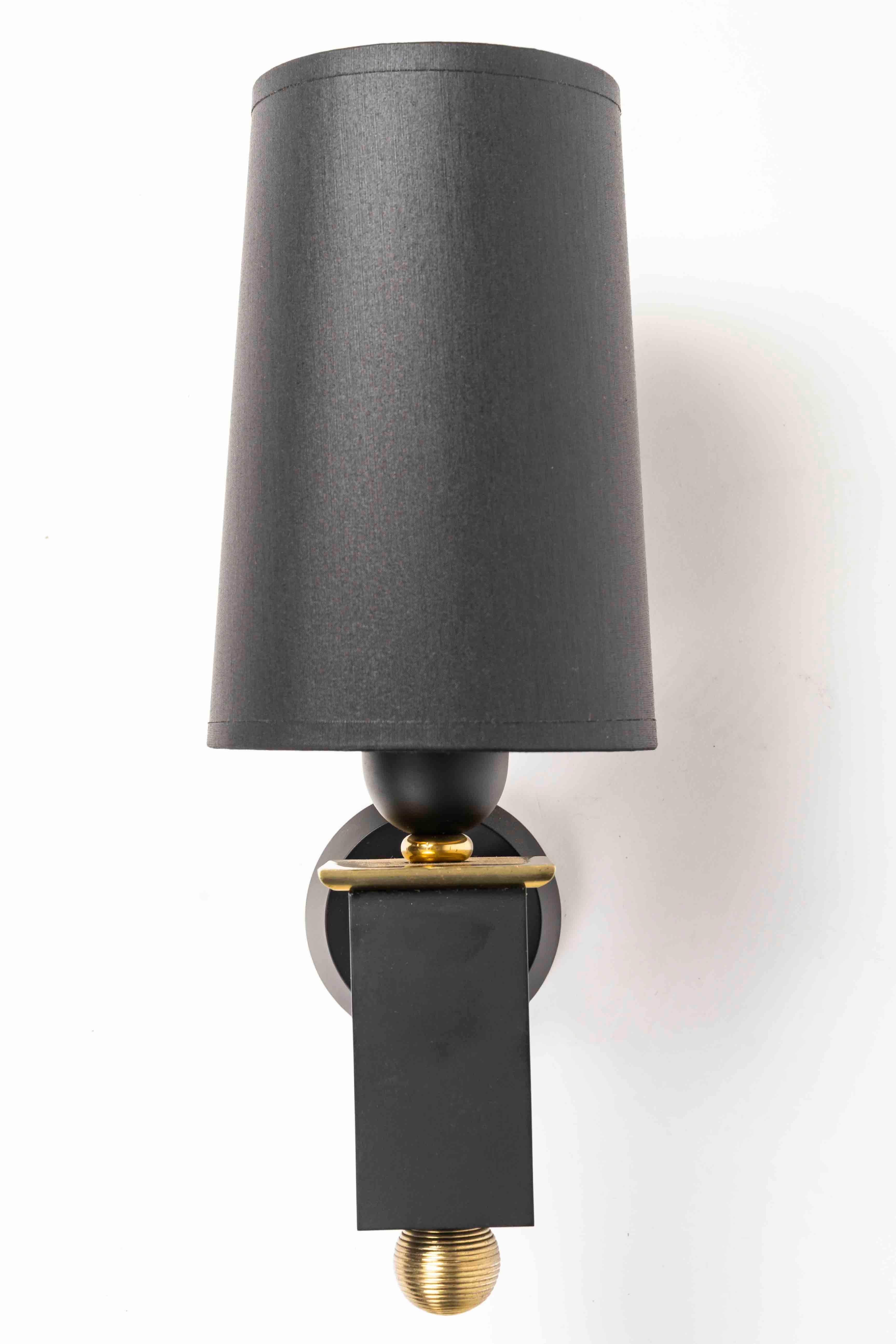 Composed of a round wall bracket on which is placed a golden brass rod supporting the lamp arm formed by a blackened bronze rectangular cube decorated at the base with a golden bronze ball and at the top with a golden bronze plate.
At the top of the