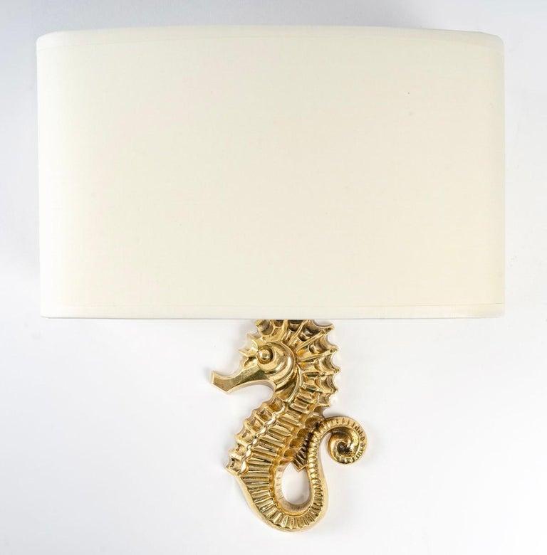 Rare model of wall sconces by Marcel Guillemard.

Composed of a gilded bronze seahorse acting as a wall support dressed with a half-shade formed by a half-screen in off-white cotton redone identically.

1 bulb per wall lamp.