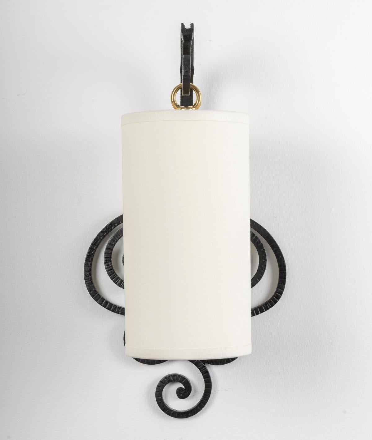 Constitué d'un support mural formé de boucles et de demi-boucles en fer forgé noir fabriquées à la main et formant un décor positionné de part et d'autre de l'applique.
Le bras de lumière en fer forgé noir est situé au sommet de l'applique,