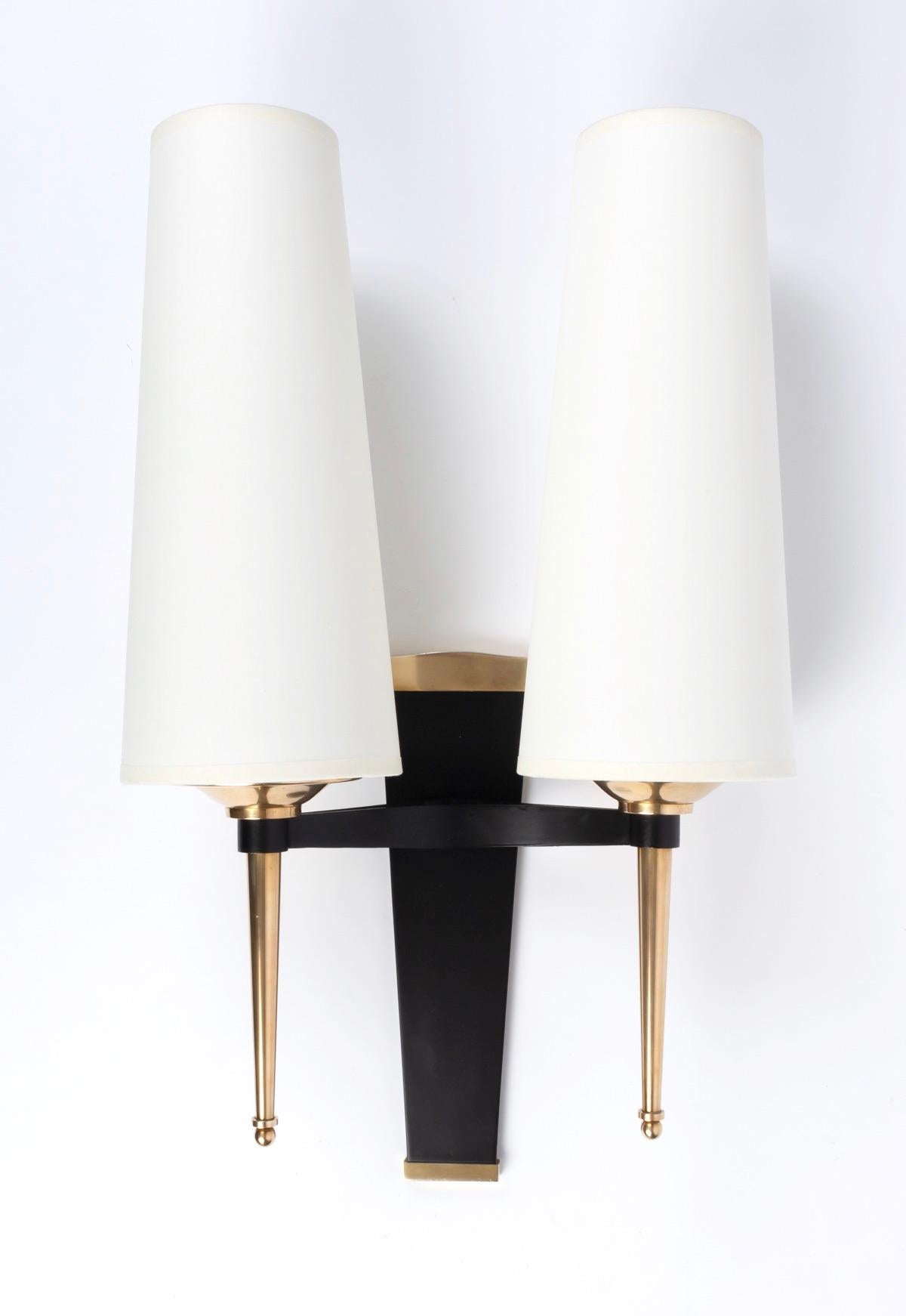 Pair of neoclassical bronze wall lights Jules Leleu, 1940
Composed of a trapezoidal base in blackened bronze highlighted by a gilded bronze band on the upper and lower part of the wall lamp.
Two bright arms in the shape of a point decorated on the