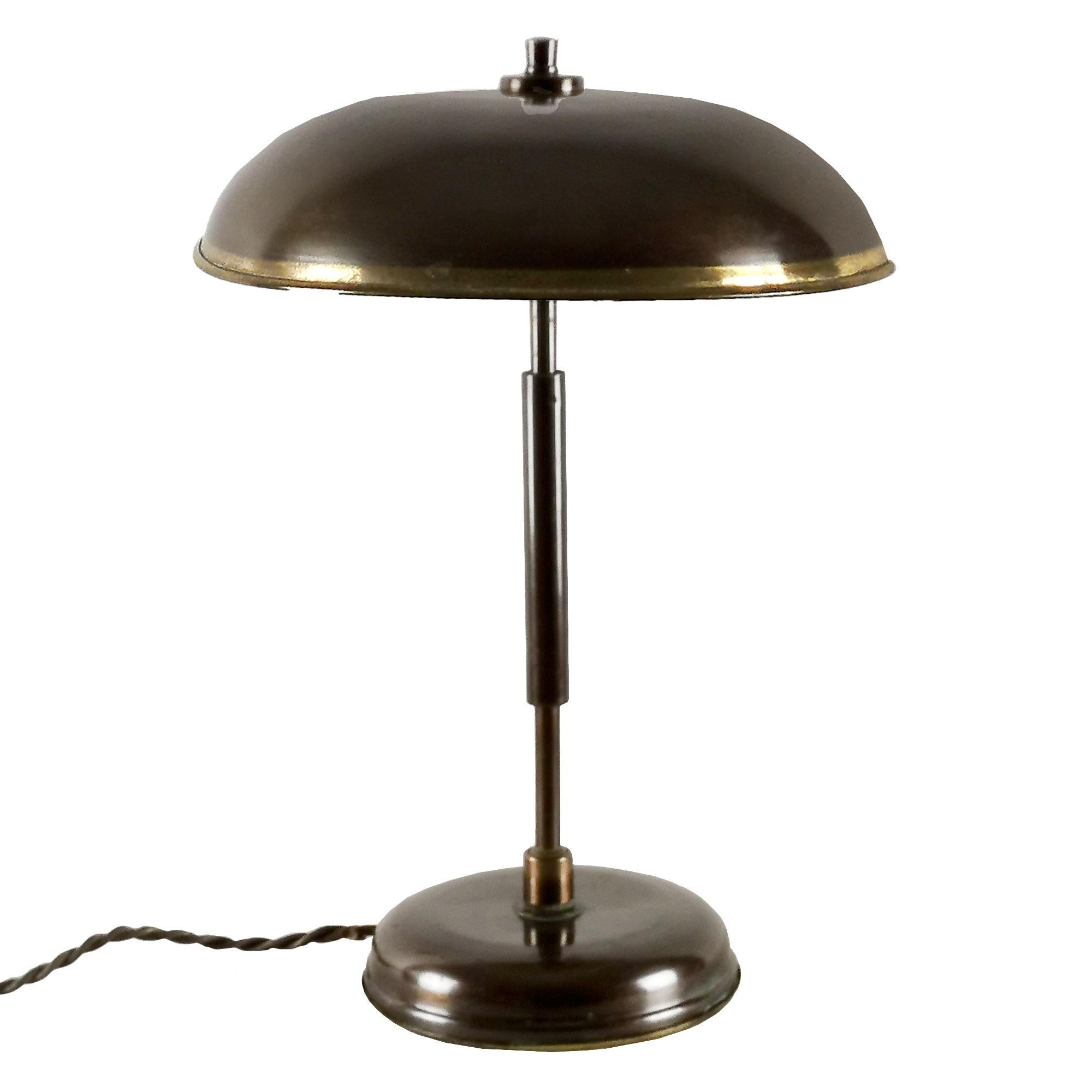 Desk lamp in patinated brass, adjustable inclination by two ball joints (one in base, one in reflector). Golden strip decoration on the reflector, two bulbs.

Italy, circa 1940