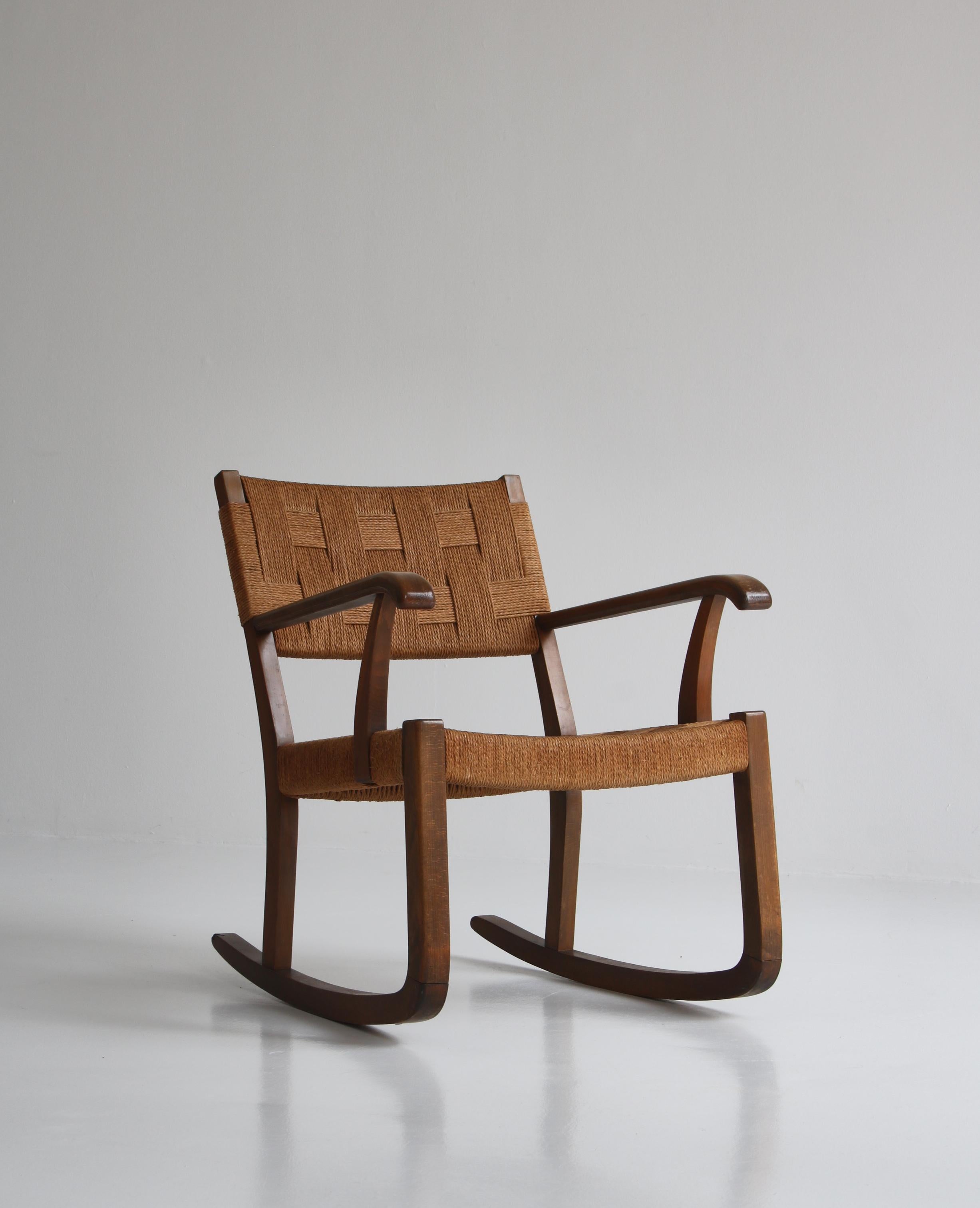 Early and rare Danish modern rocking chair in dark stained beech and seagrass manufactured by Fritz Hansen, Copenhagen in the 1940s and attributed to architect Karl Scröder who made a lot of similar models for Fritz Hansen. The rocking chairs is in
