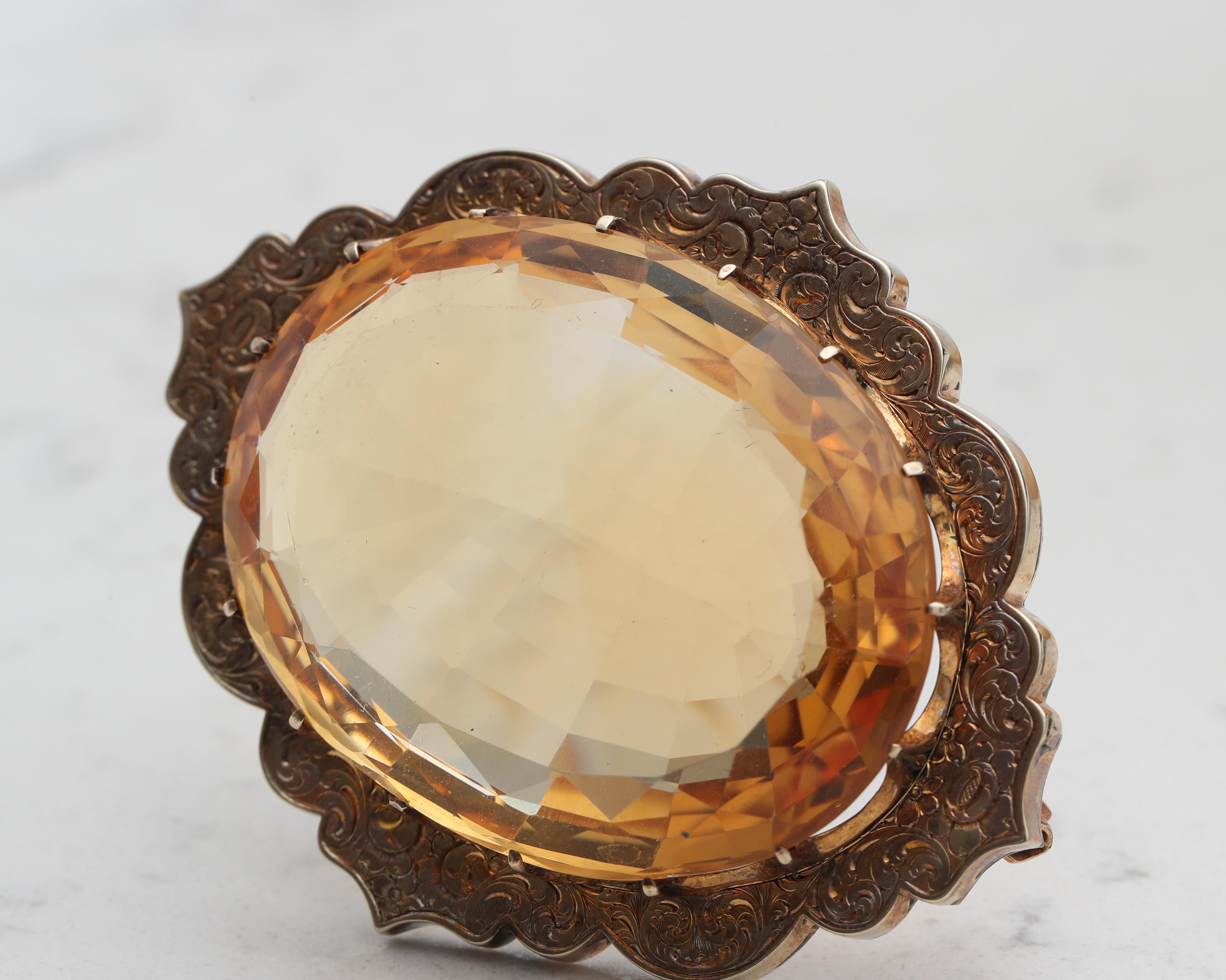Ornate Citrine Brooch from the 1950s. The citrine is approximately 100 carats, in great condition with minor scratches. Beautifully crafted brooch with intricate details in 14 karat yellow gold. It's a bold statement piece with a lot of vintage