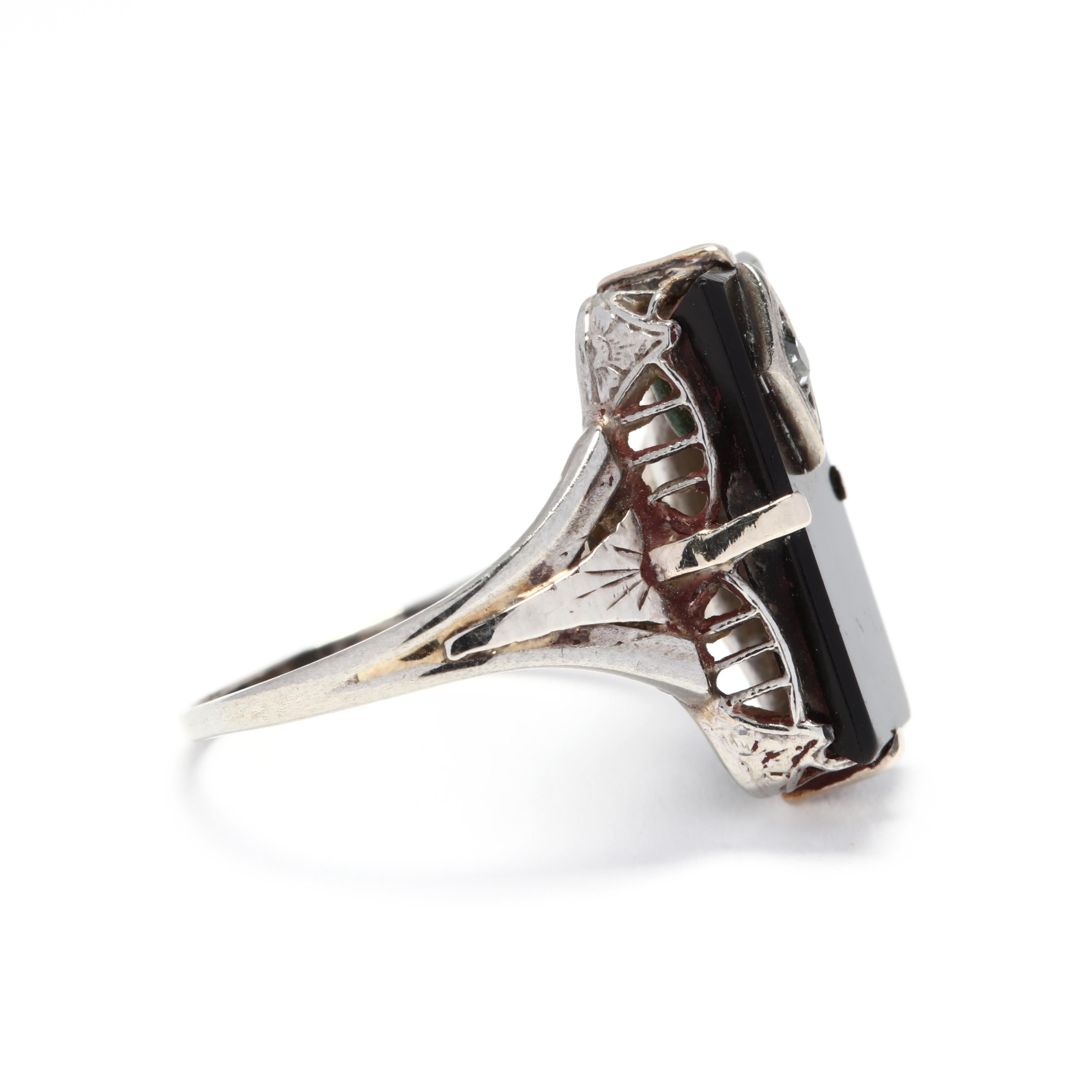 A 1940's 10 karat white gold diamond and black onyx rectangle ring. This ring features a black onyx table stone with a single cut diamond set in a white gold marquise station in the black onyx table and with floral and filigree detailing.

Stones:
-
