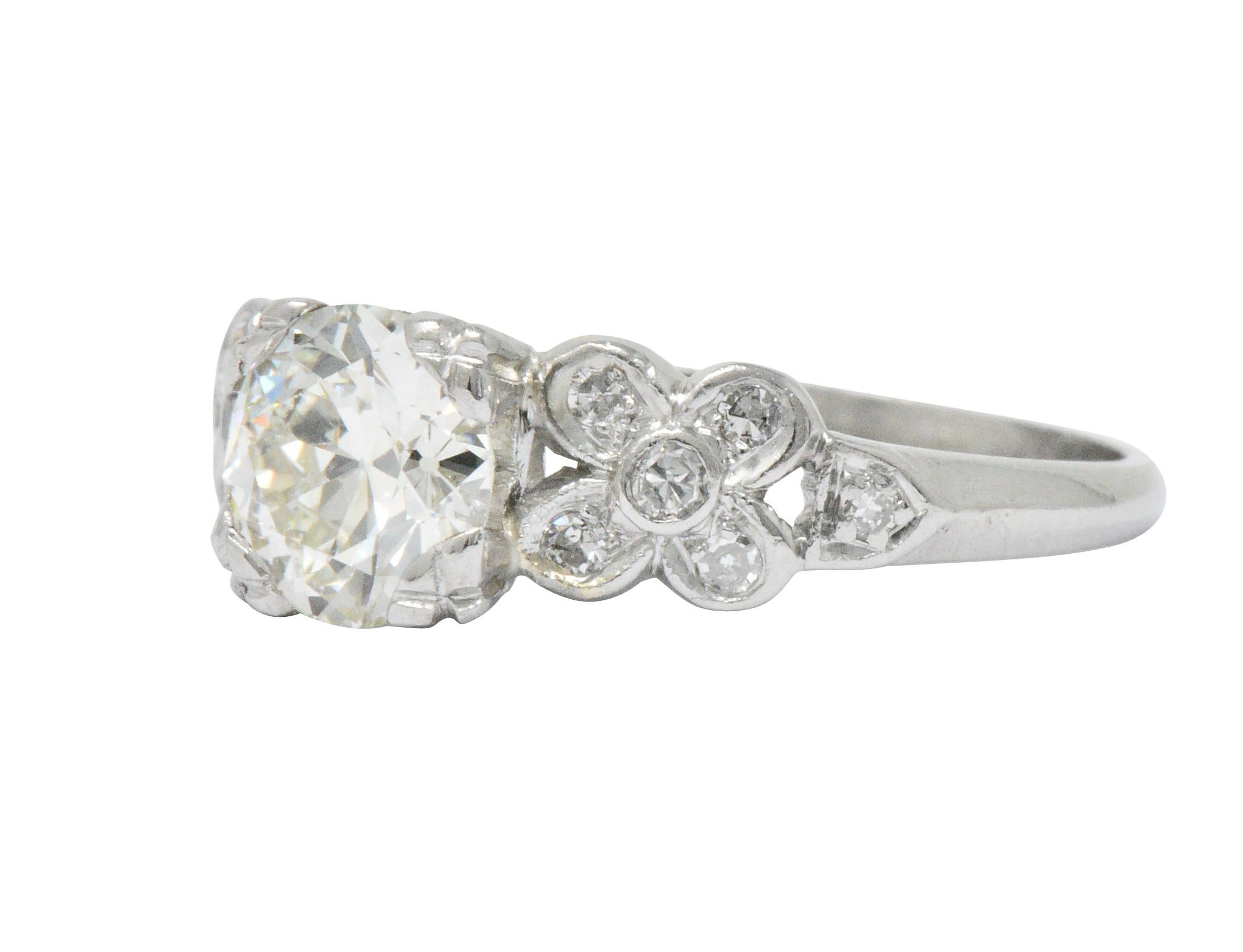 Centering an old European cut diamond, set securely with decorative prongs, weighing 1.10 carats; L color with VS1 clarity

Flanked by floral motif shoulders accented by single cut diamonds, weighing approximately 0.11 carat total; eye-clean and