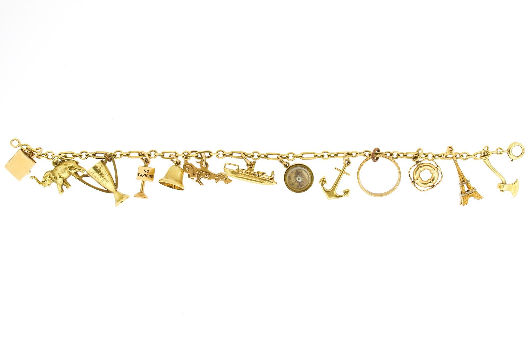A fully finished 1940s vintage charm bracelet set with thirteen 14k yellow gold charms. The charms are all articulated and beautifully rendered. The charms are: A case that opens (now empty), an elephant, a trophy dated 1937, a No Parking sign, a