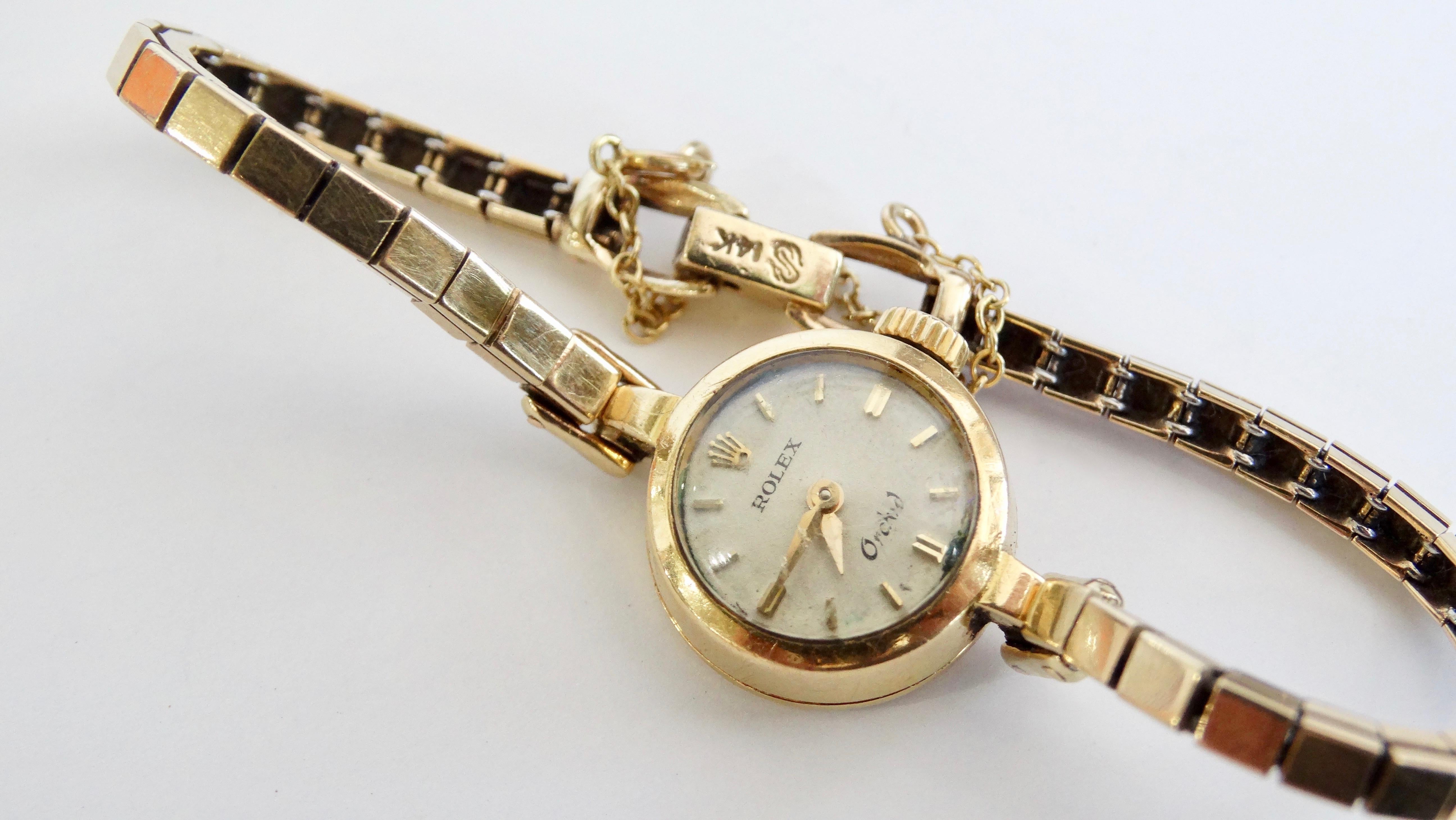 Gorgeous Rolex Orchid ladies watch crafted of 14kt Gold. Features a white dial and gold number markers and a manual wind. Stamped on the back with the Rolex logo. 
Weighs 15.11 grams. Perfect piece to stack with other bracelets 7inches long
