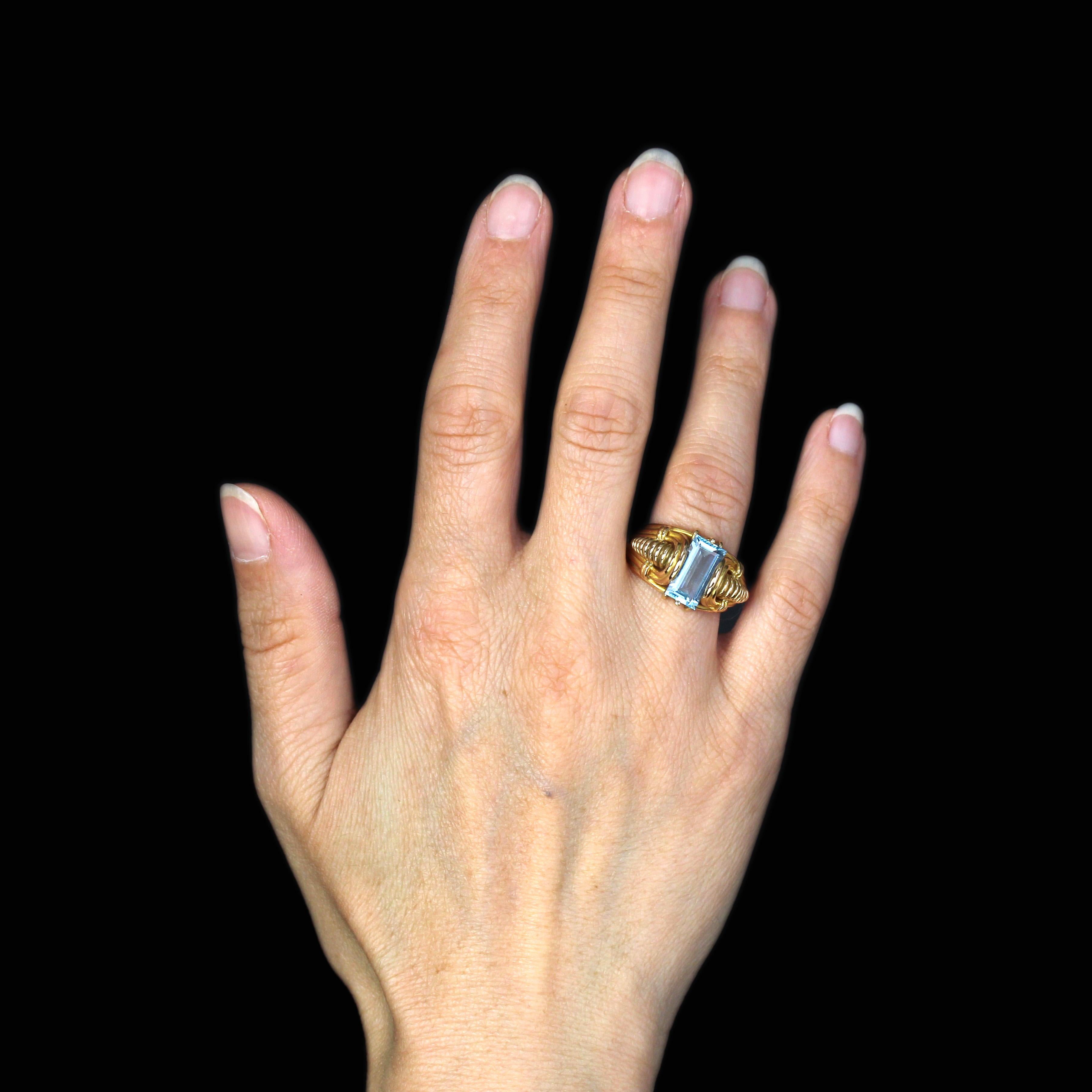 Anello in oro giallo 18 carati, marchio proprio.
Magnifico e originale anello antico in oro, è decorato sulla parte superiore con un'acquamarina rettangolare tagliata a gradi. Su entrambi i lati, l'anello è formato da una decorazione con gadroons