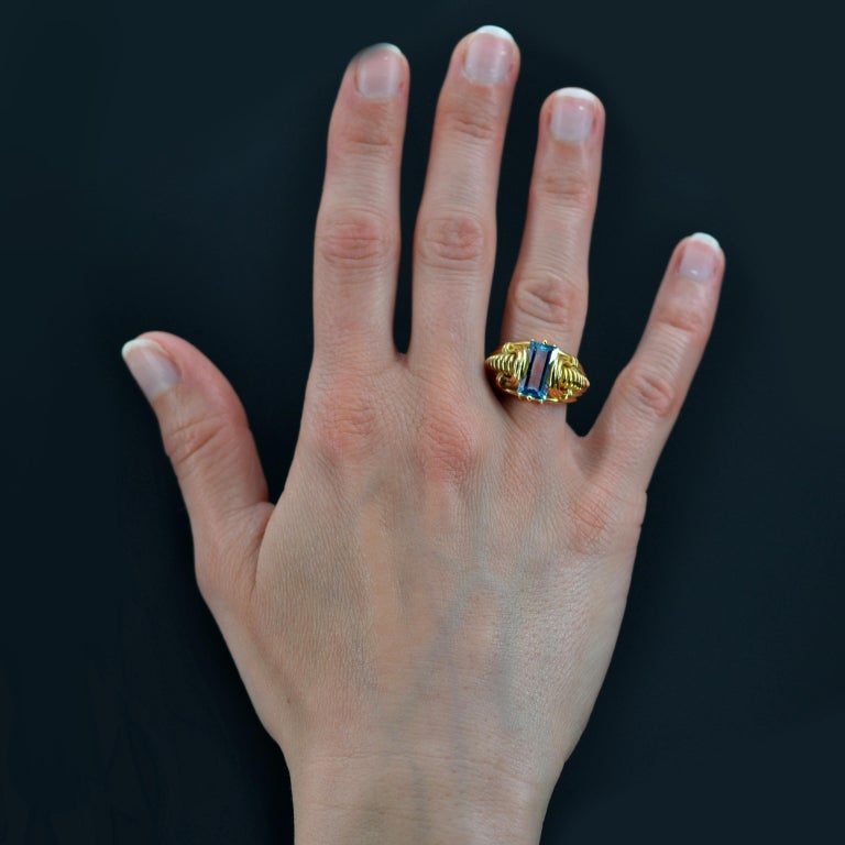 Ring in 18 karat yellow gold.
Magnificent and original antique ring in gold, it is decorated on its top with a degrees- cut rectangular aquamarine. On both sides, the ring is formed by a decoration with openworked gadroons and a tubogas.
Weight of