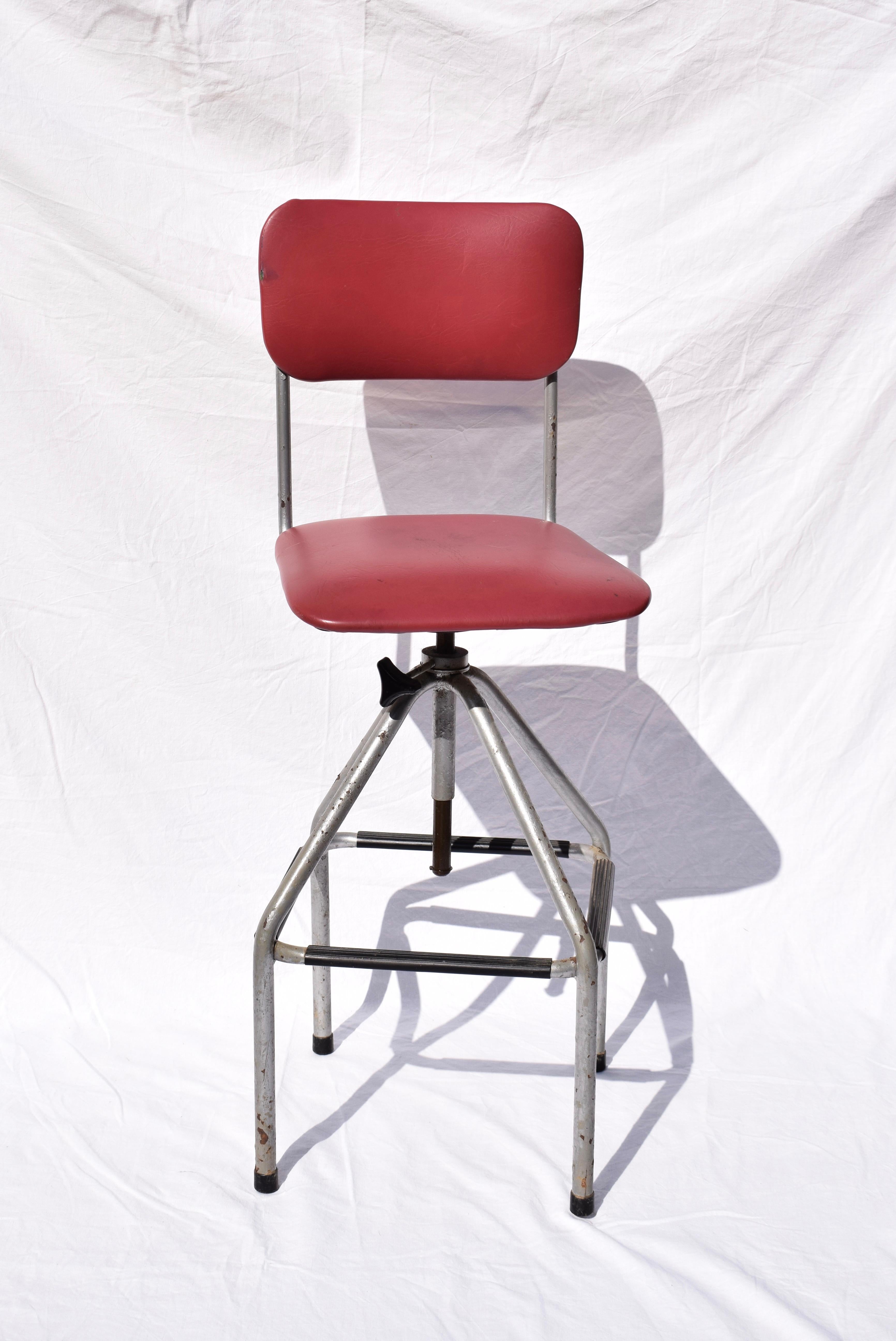 A tall English drafting or as an operators chair probably from the 1940s - 1950s. It would have been used by a telephone operator which means that the stool has been designed with practical features to make it comfortable to use. The seat is