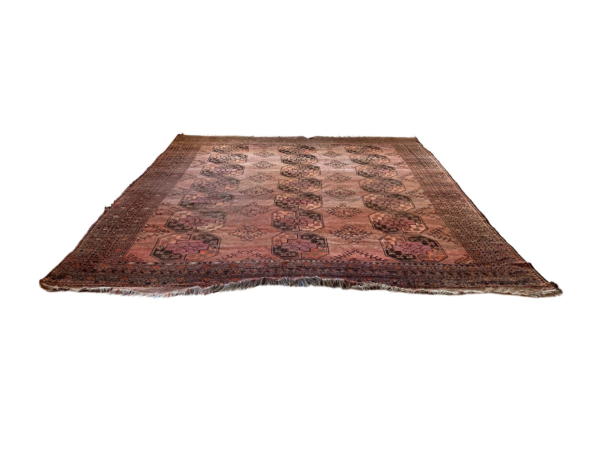 Large Afghan Bokhara rug, hand-woven in the 1940s. It features the traditional guls arranged in a row on a rust-red field, surrounded by bands with geometric floral patterns.

Dimensions:
12' 2