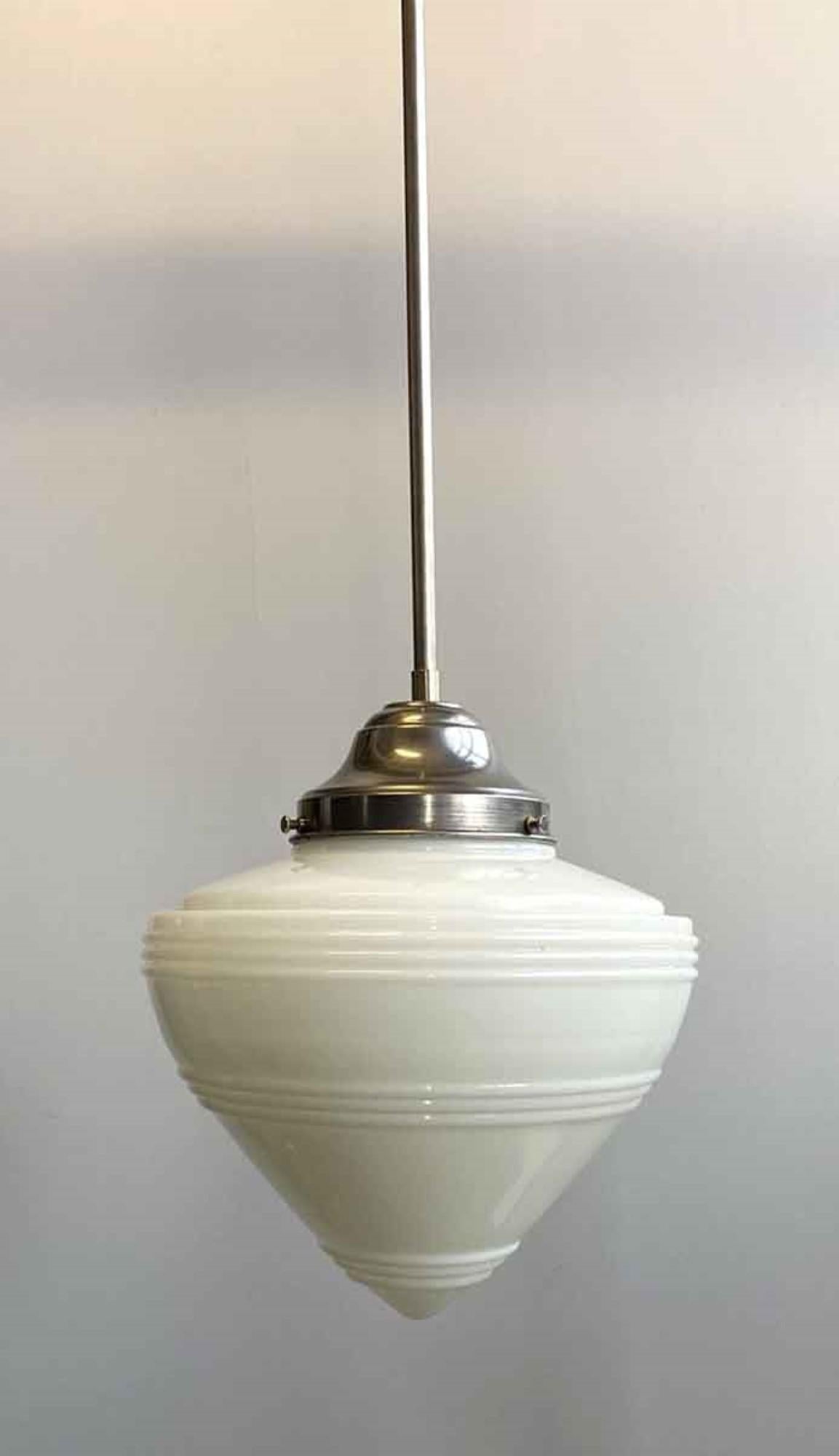Lampada a sospensione in stile Streamline degli anni '40 con globo di vetro bianco a forma di cono su montatura in acciaio spazzolato. Questo può essere visto nella nostra sede di 400 Gilligan St a Scranton. PA.