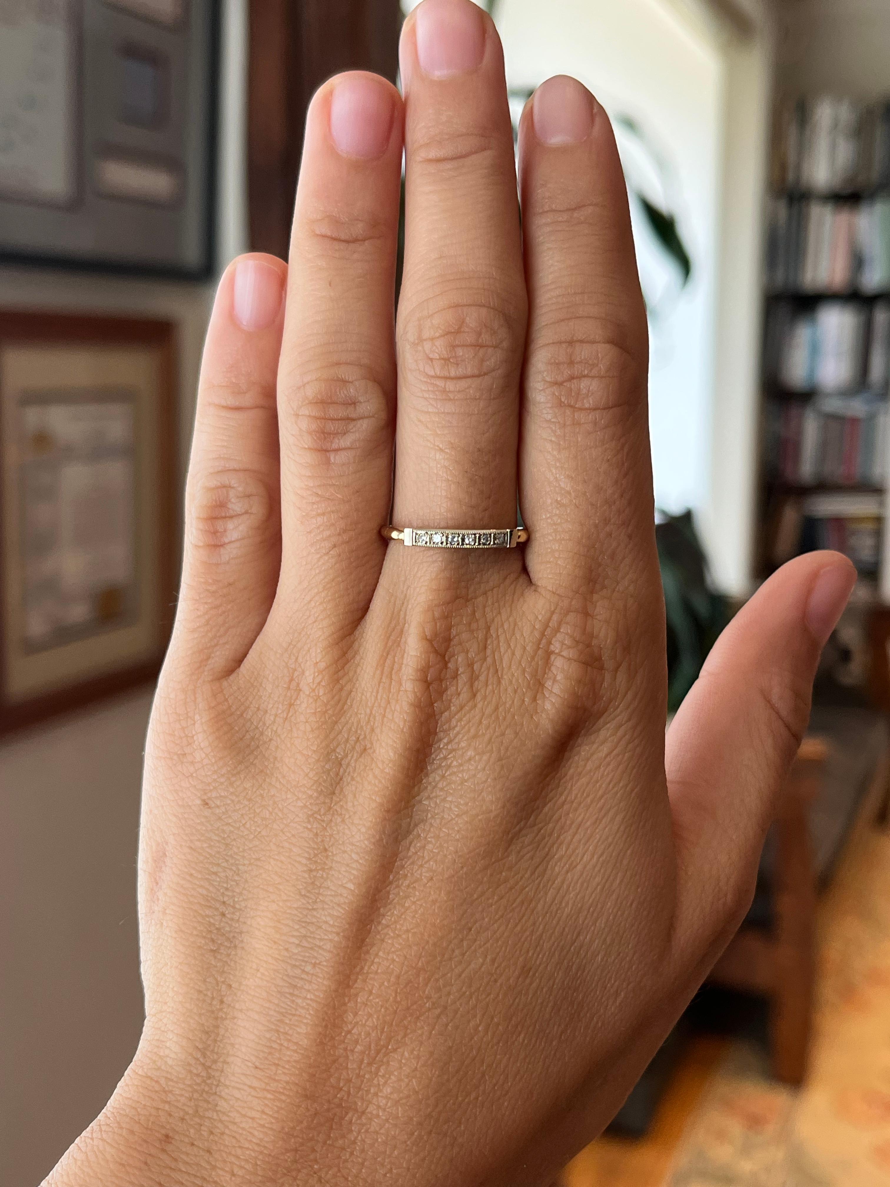 This antique 14K two-tone white and yellow gold wedding band is a fine piece from the 1940s, featuring 6 single cut round diamonds that total 0.09ct. It features milgrain details bordering the stones and measure 2.3mm at the top. It is one of many