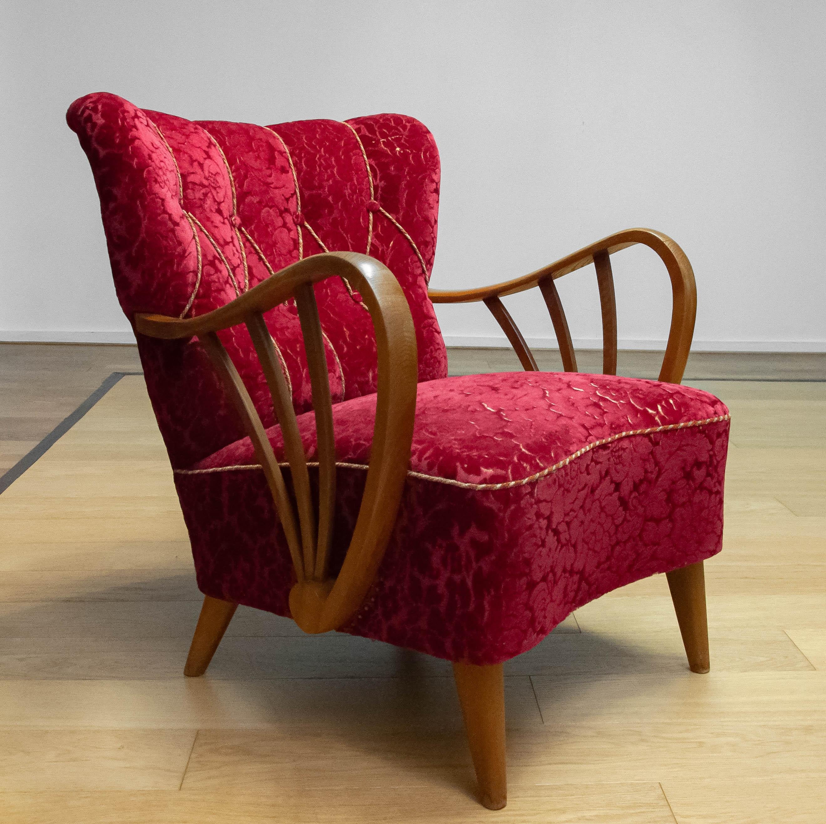 Se trata de una silla fabricada por Sternells en Virserum, Suecia, durante la década de 1940.
La silla presenta su lujoso tapizado original de terciopelo en un tono rojo intenso, bellamente complementado por unos esculturales reposabrazos y una
