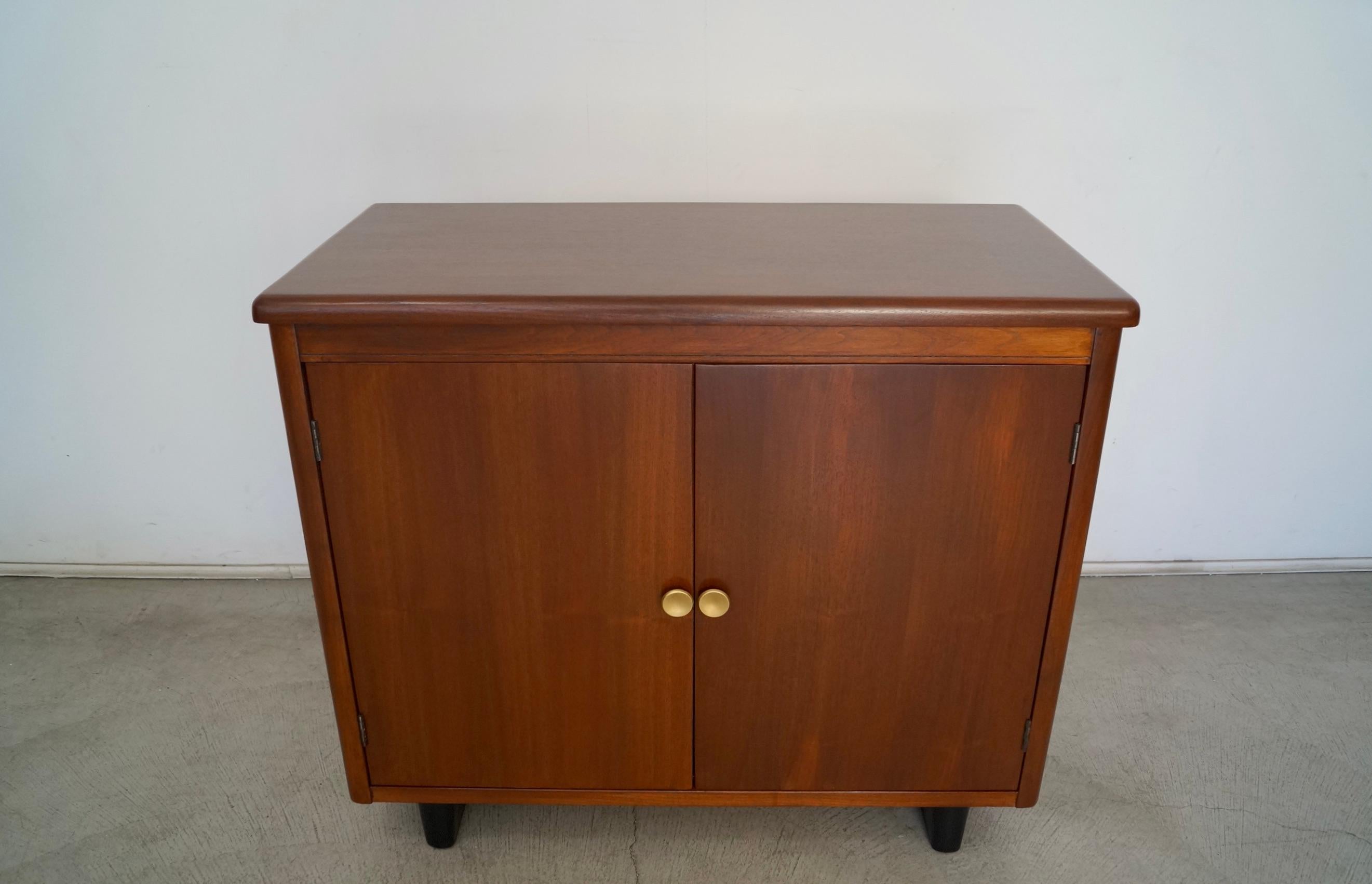Vintage Midcentury Art Deco cabinet for sale. Manufactured in the 1940's, and has been professionally refinished. It's made of walnut, and has two solid sled bases in black. It was manufactured by Nucraft, and was made in Grand Rapids, Michigan. The