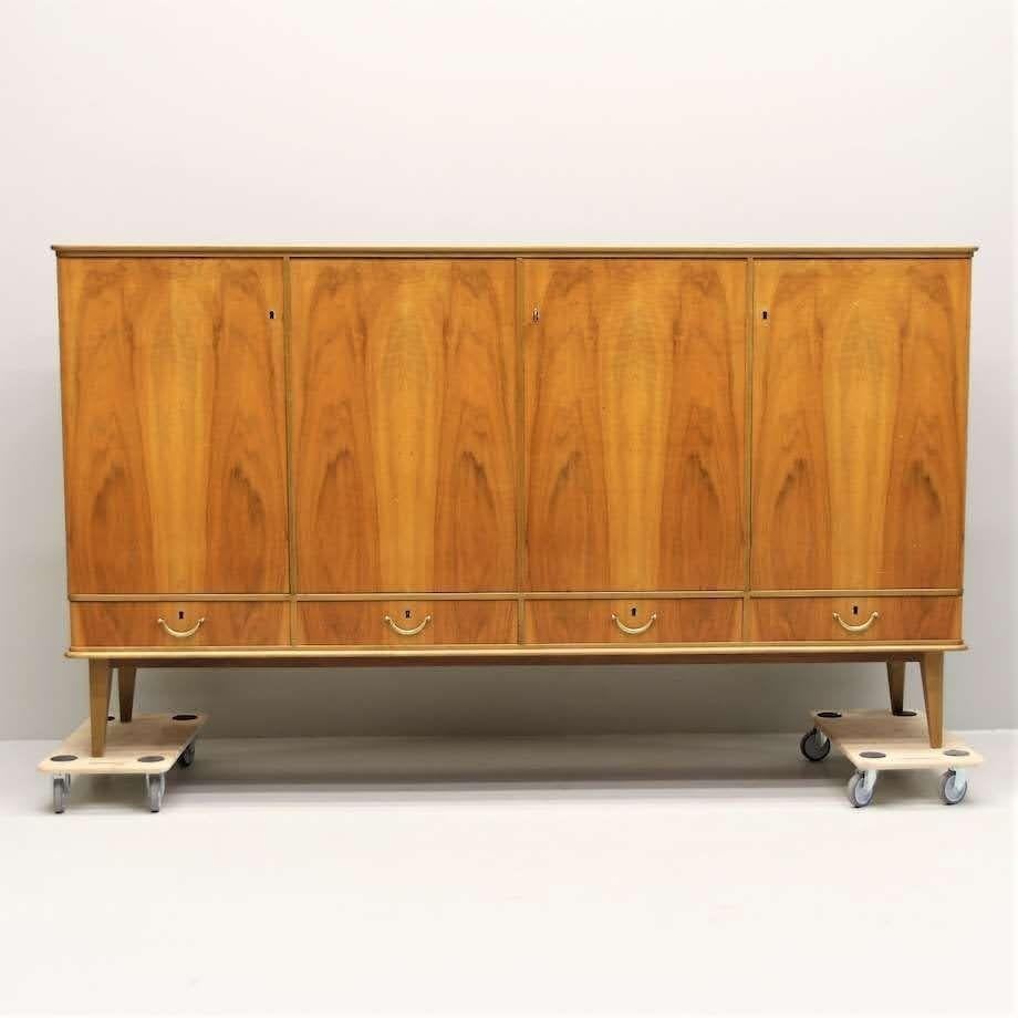 1940s Art Deco credenza with gorgeous veneer and original hardware. Three drawers at bottom and four cabinet doors open to reveal interior shelving and three flat drawers, providing ample dining or kitchen storage, making this piece as useful as it