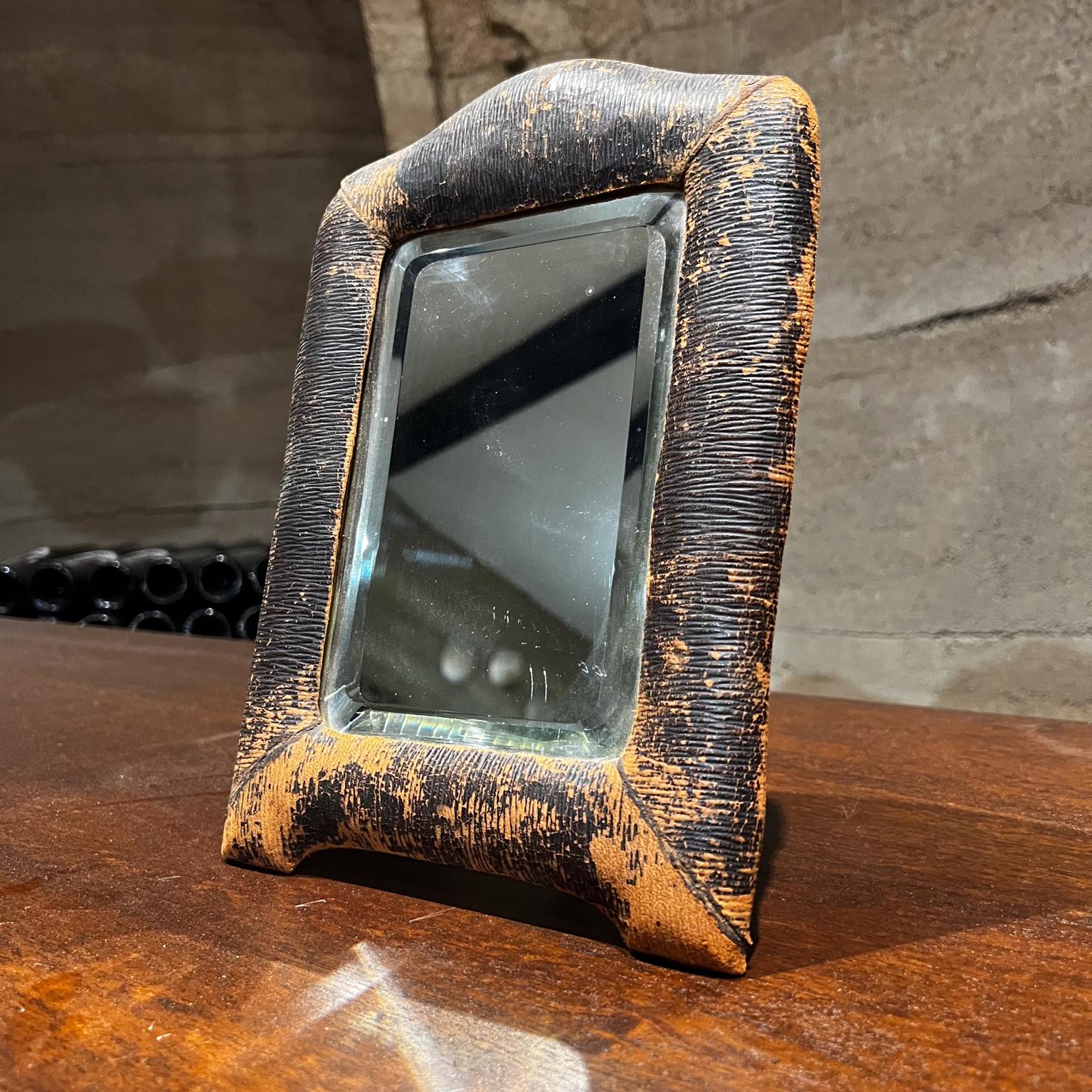 We presents
Vintage table mirror constructed with wood frame wrapped leather. The brown leather has a specific print pattern. The mirror has a beautiful, beveled edge with a smooth transition around the corners. The flat screws are original to the