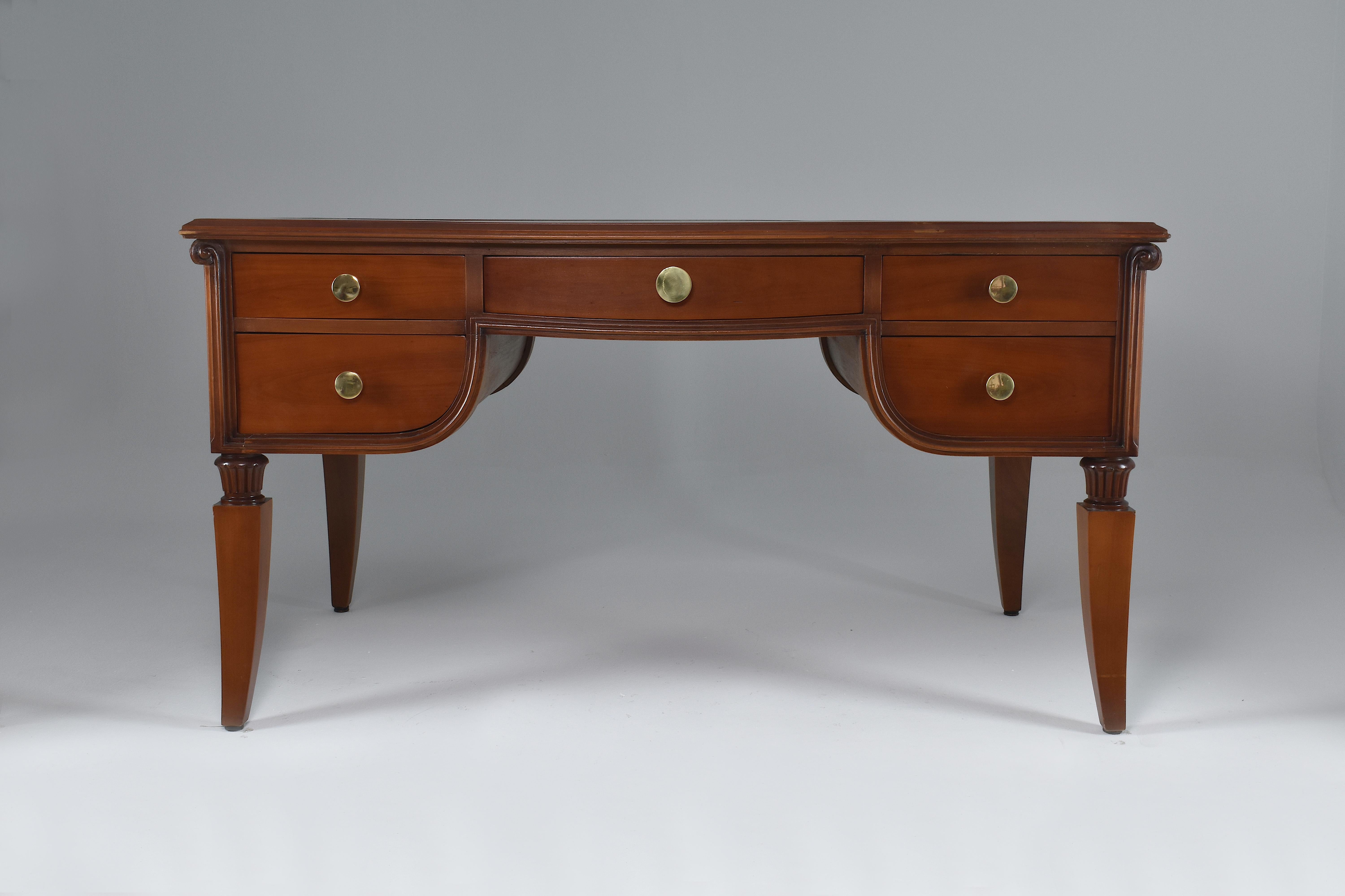 A majestic 20th-century French vintage office desk with beautiful sculpted neo-classical style details and big brass handles. This desk is composed of one central drawer and two additional drawers on each side. The leather 
France. 1940's