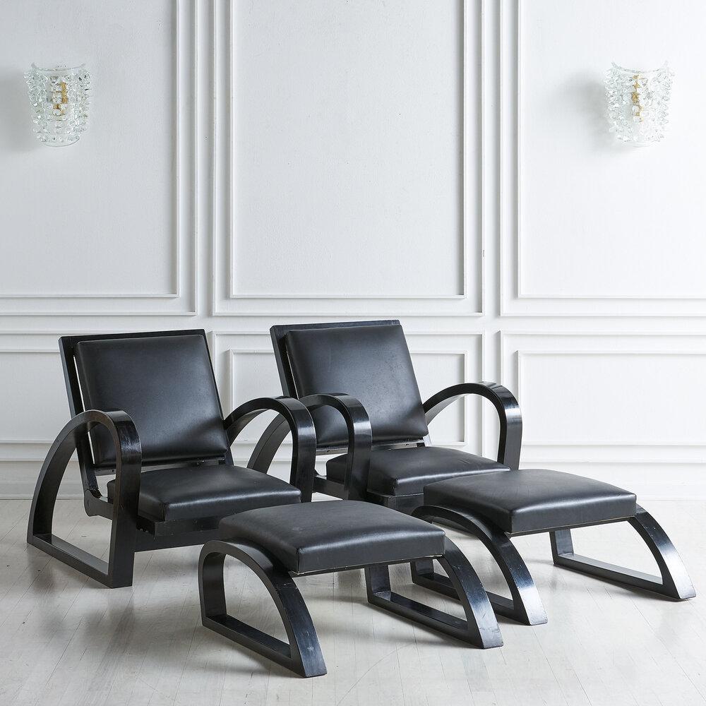 A pair of Art Deco Italian Lounge chairs featuring a black wood frame and black leather upholstery with frames that adjust and allow the seat to recline slightly.

Dimensions: Chair: 29” H x 27.25” W x 40.5” D, seat height 12”; Ottoman: 13” H x